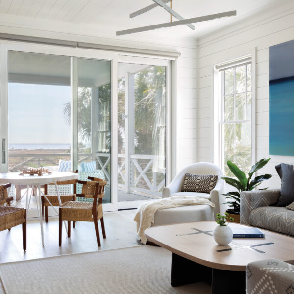 A Master Of Southern Coastal Vernacular Completes A Sullivan’s Island Retreat For Generations To Come Family room overlooking the ocean featuring upholstered seating, oval coffee table, game table with chairs and sliding screen doors to a porch