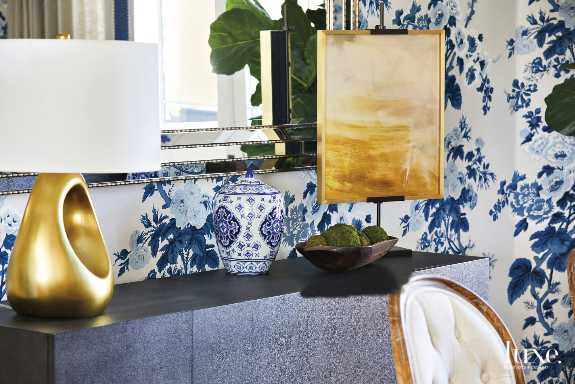 A vignette in the dining room with Chinoiserie-style porcelain and blue-and-white floral wallpaper.