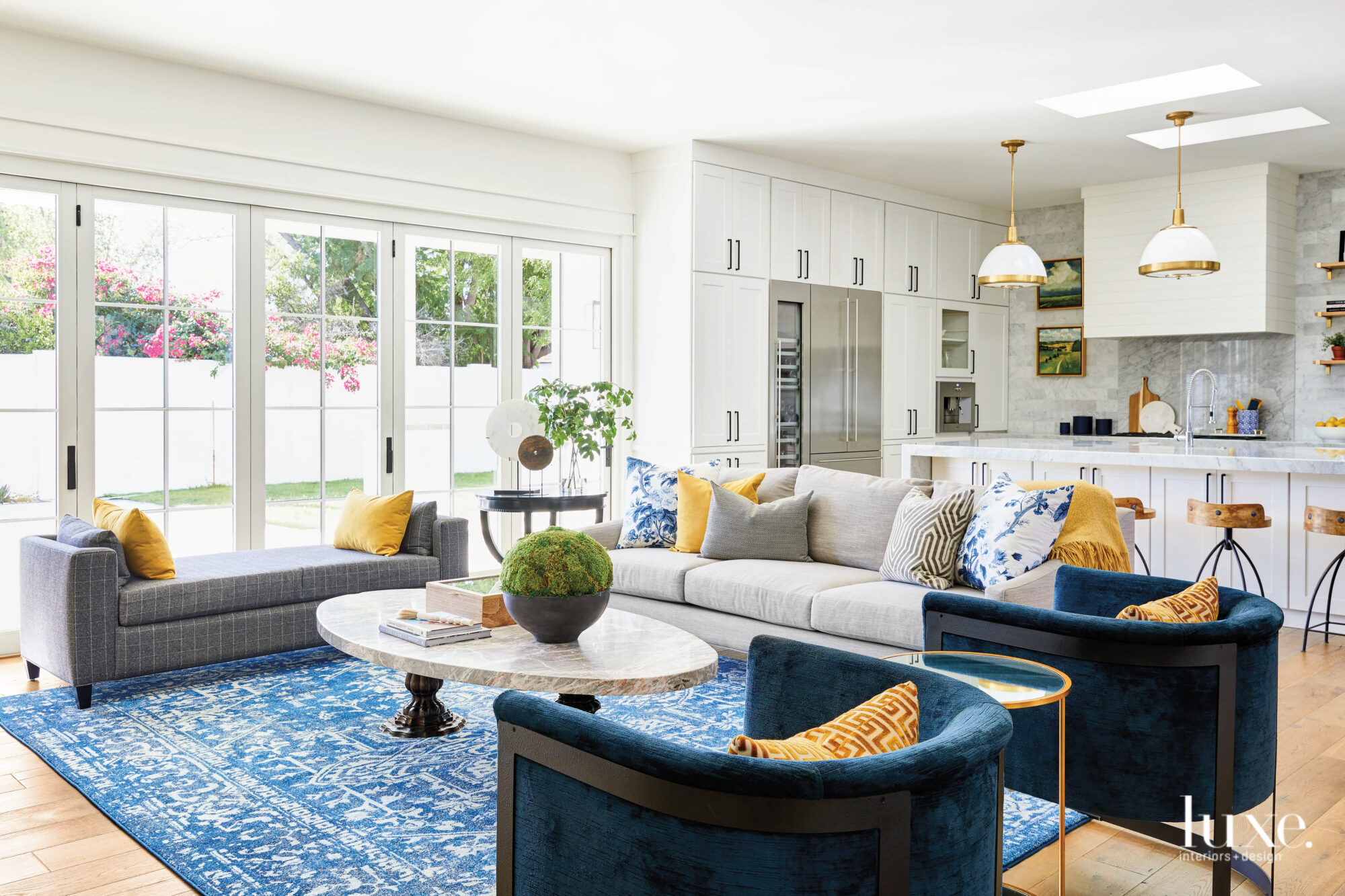 The living room is a mix of blue and gray furniture, a blue rug and yellow accents.