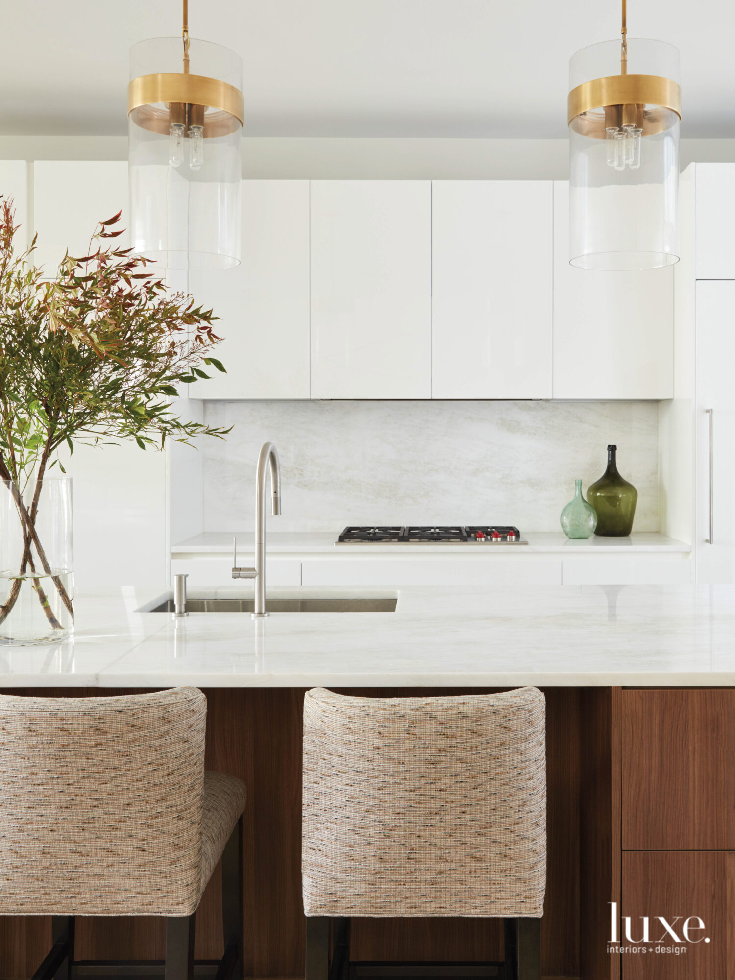 The kitchen has white cabinets, a wood island topped with marble and a marble backsplash.