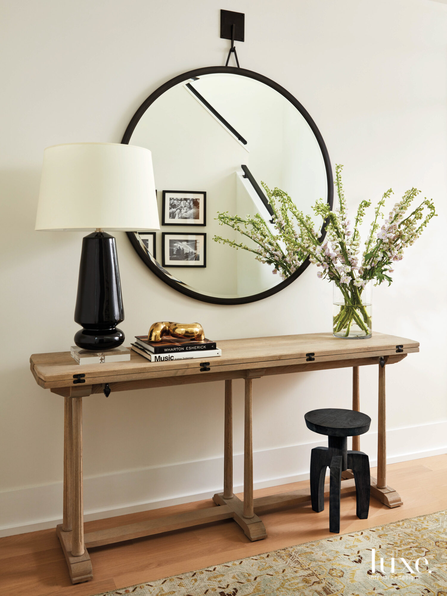 A wood console topped with a back lamp sits in the entry. A black-framed mirror hangs above it.