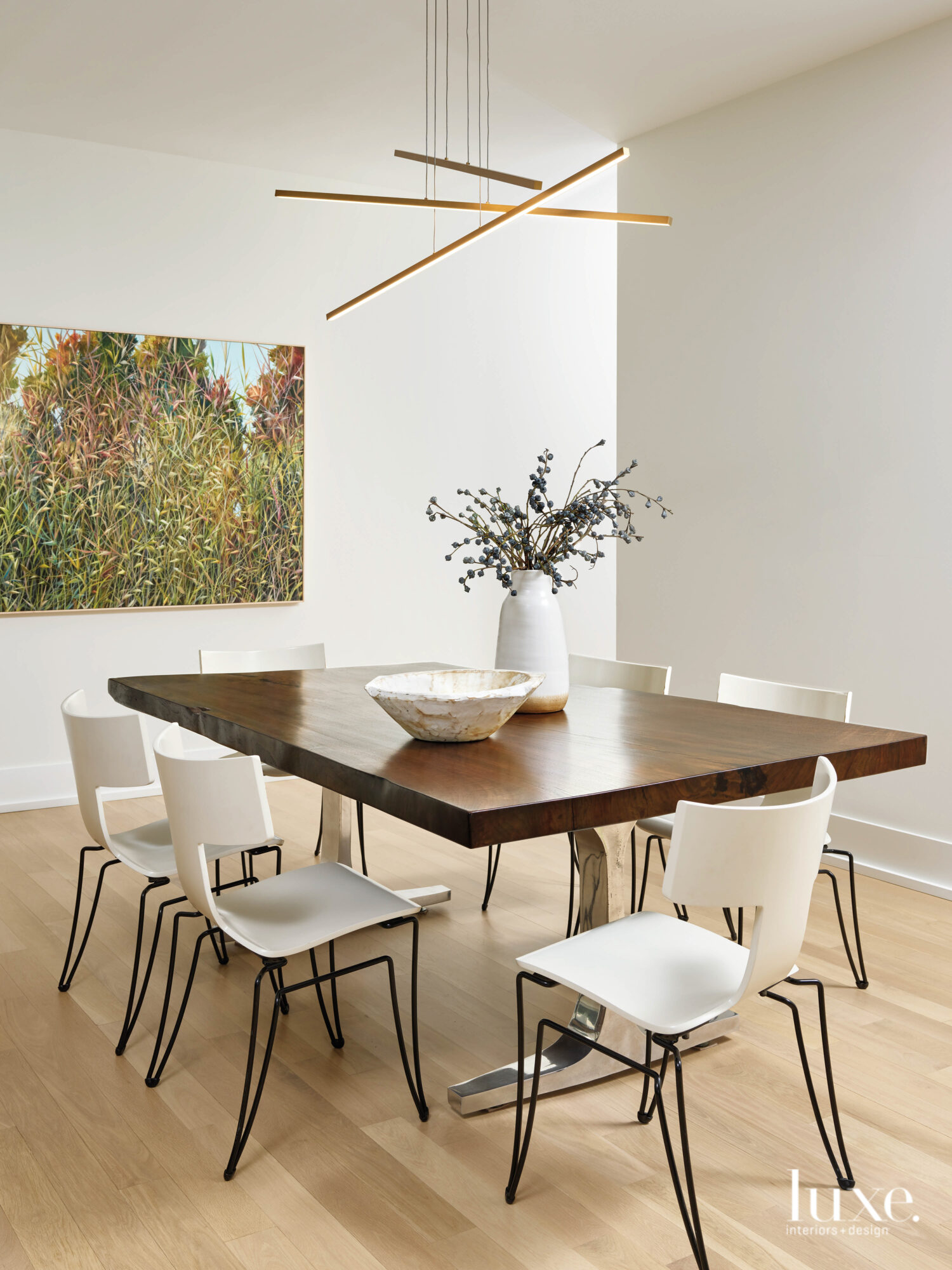 The dining room is minimal with a wood-topped table and modern white chairs.