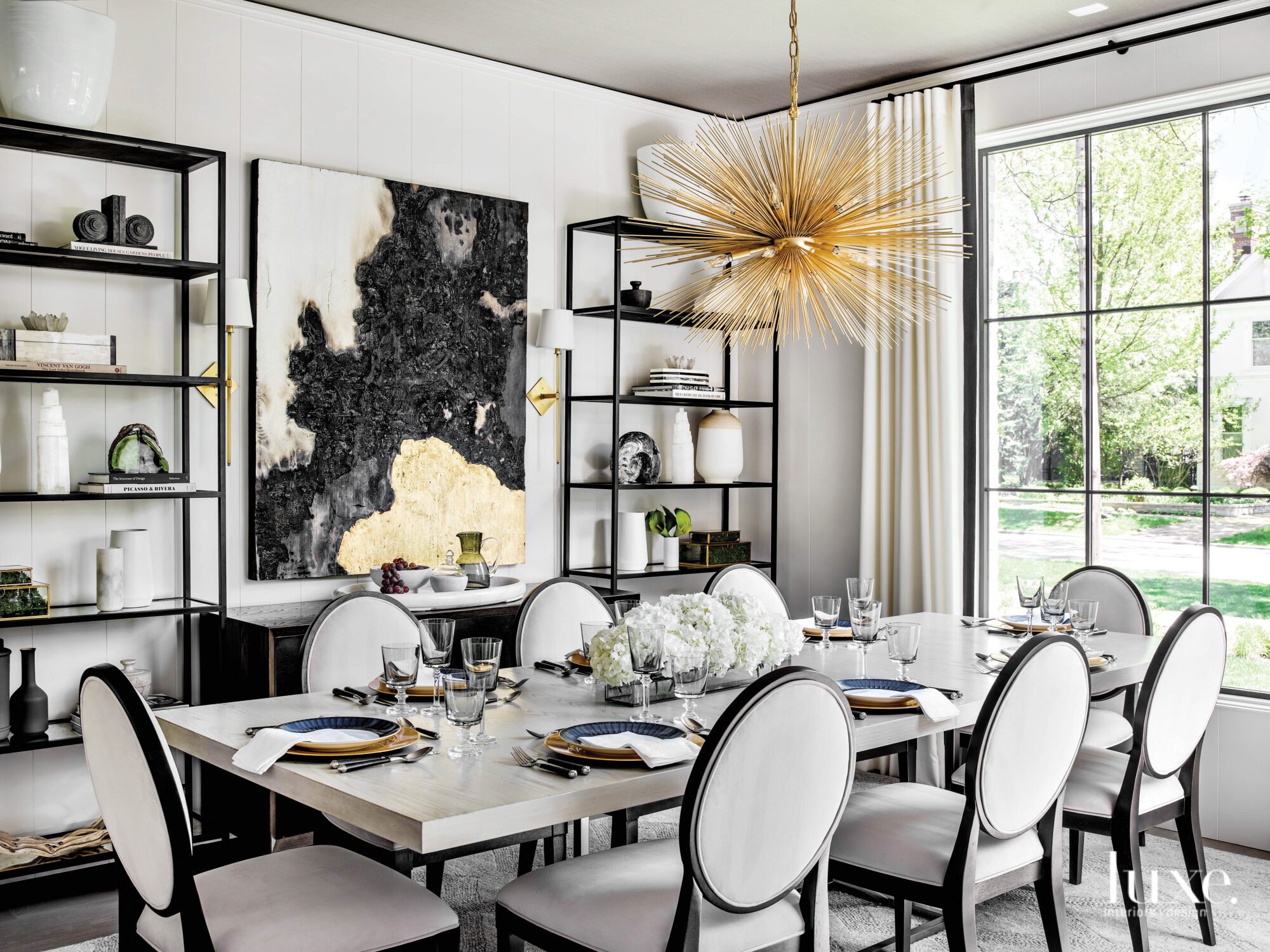 The dining room is decorated in black, white and gold, including a dramatic chandelier and a painting featuring gold leaf by Cleveland Dean.