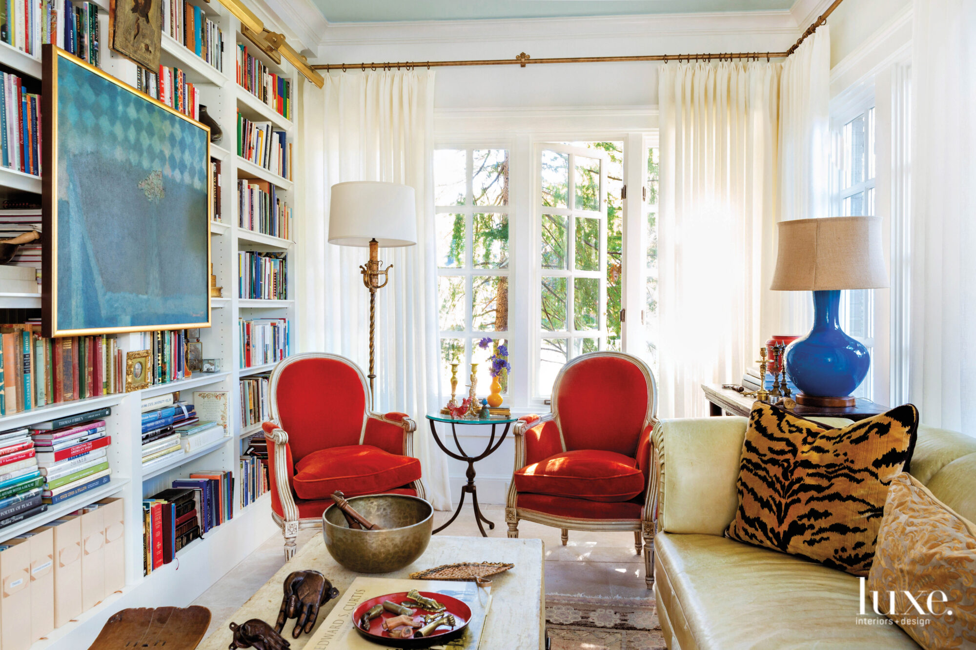 Small living room with built-in bookshelves, red armchairs and open French doors