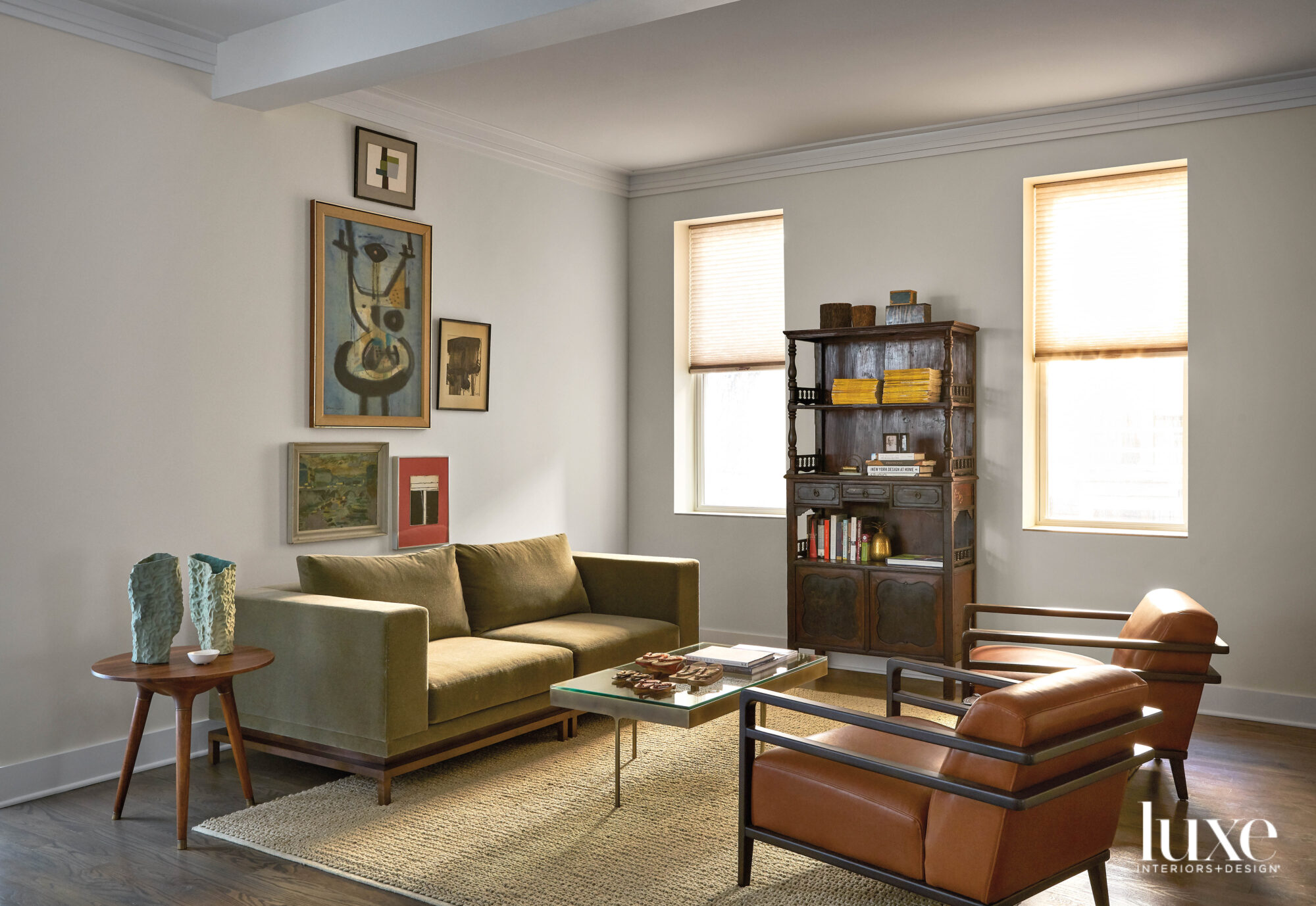 Eclectic artwork hangs above an olive green couch, which faces two leather armchairs.
