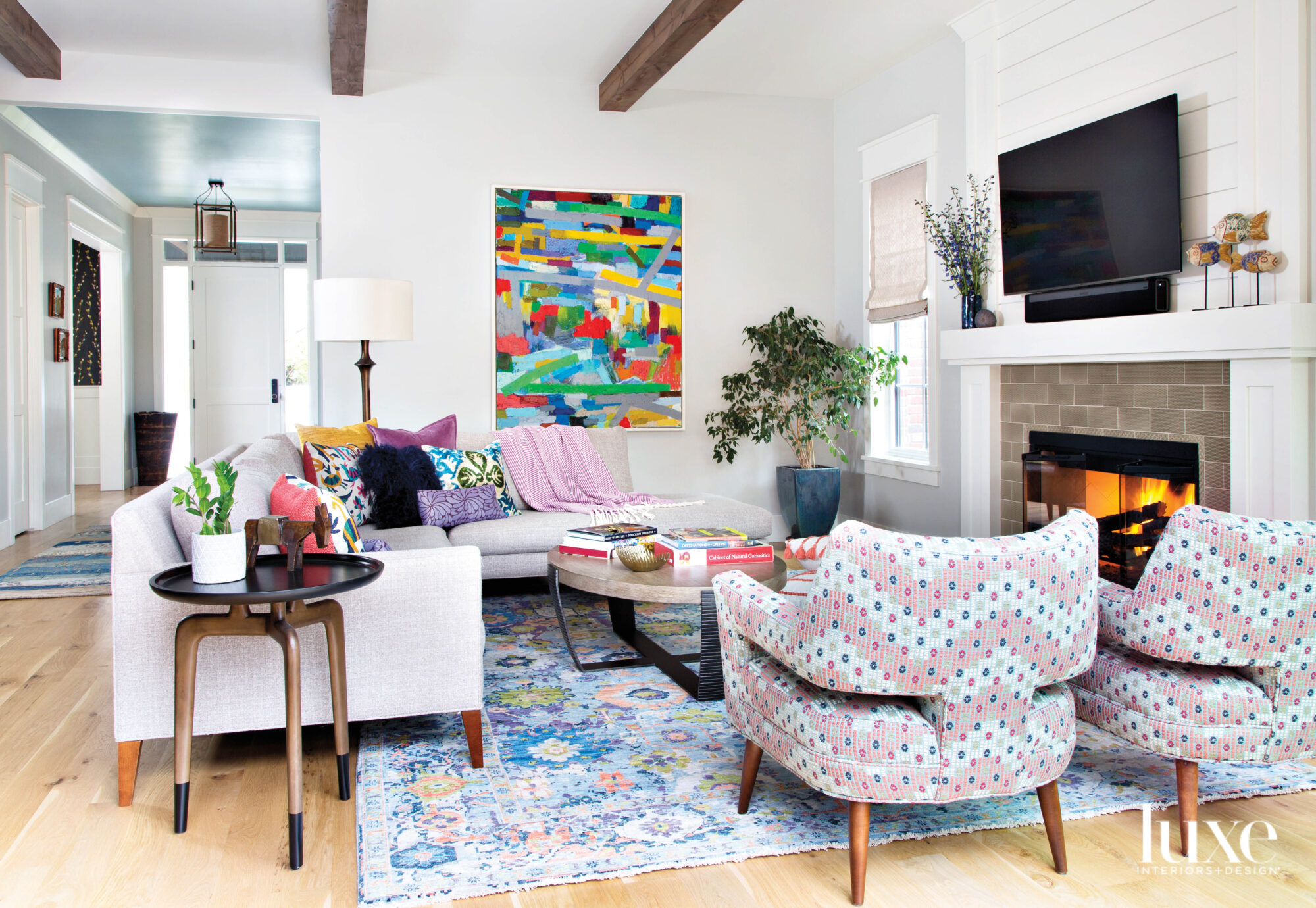 The living room has doses of bright color in the art, upholstery and rug.