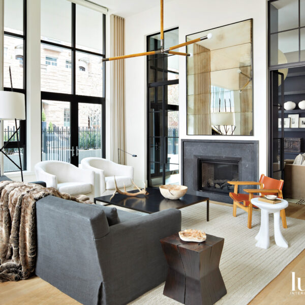 A living room is arranged around a fireplace composed of black stone and mirrored panels.