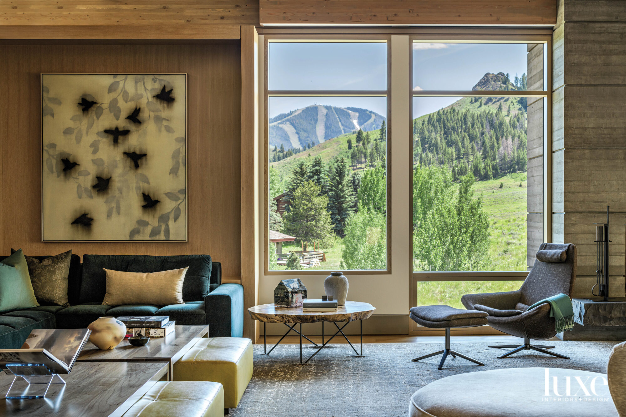 subdued living space with blue couch, eames-style chair and window with landscape views 