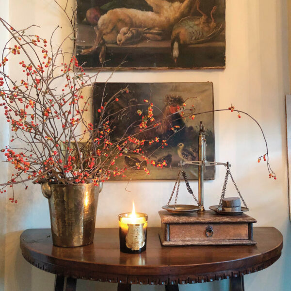 small table with artwork above and tall flowers