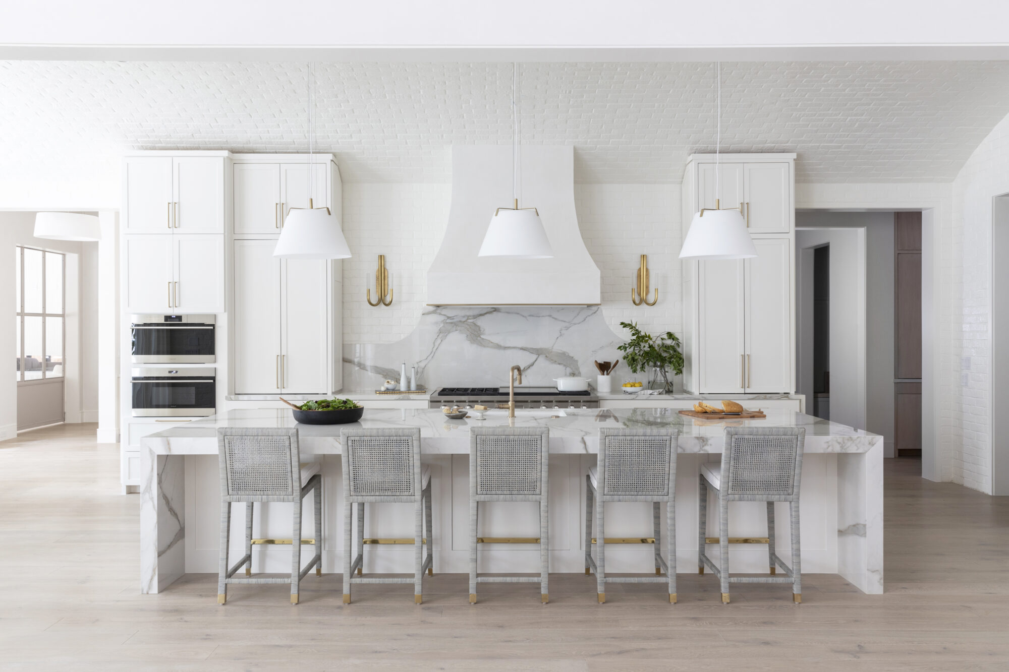 all-white kitchen design with matching counter stools, counter, cabinetry, and stove range and hood