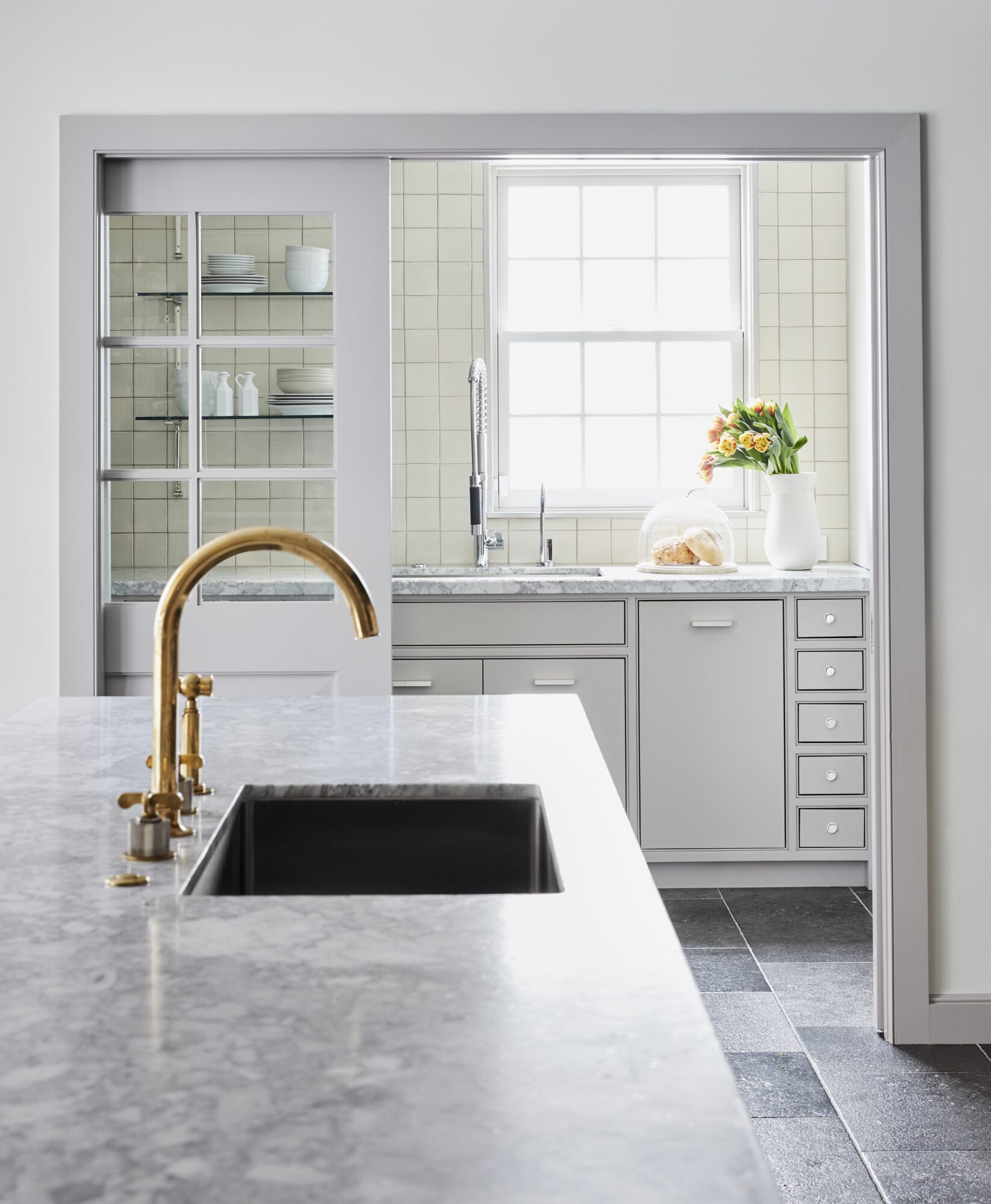 white kitchen pantry with golden faucet, grey marble sink and shelves