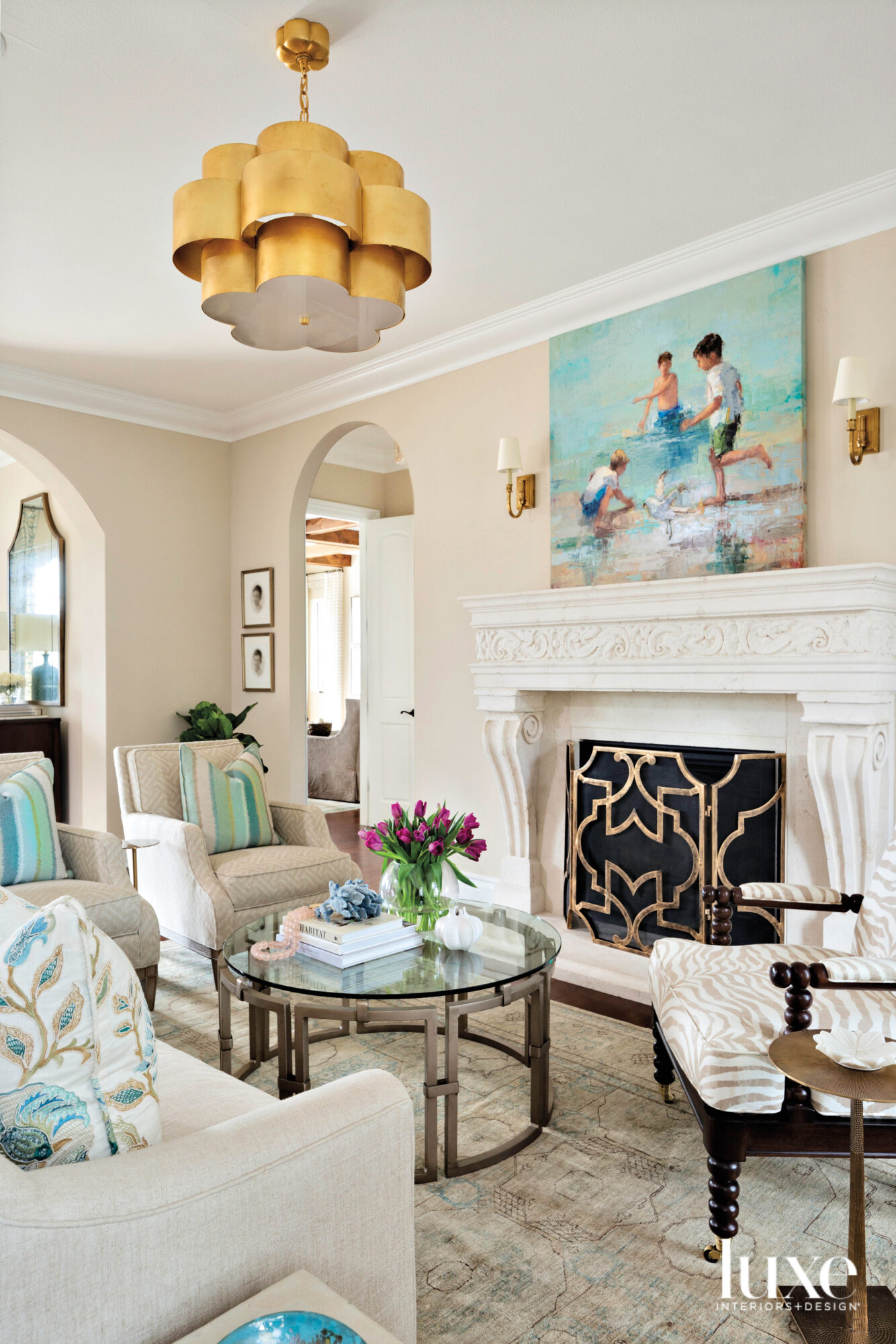 Cream-colored living room with accents of blue and green, and a gold light fixture.