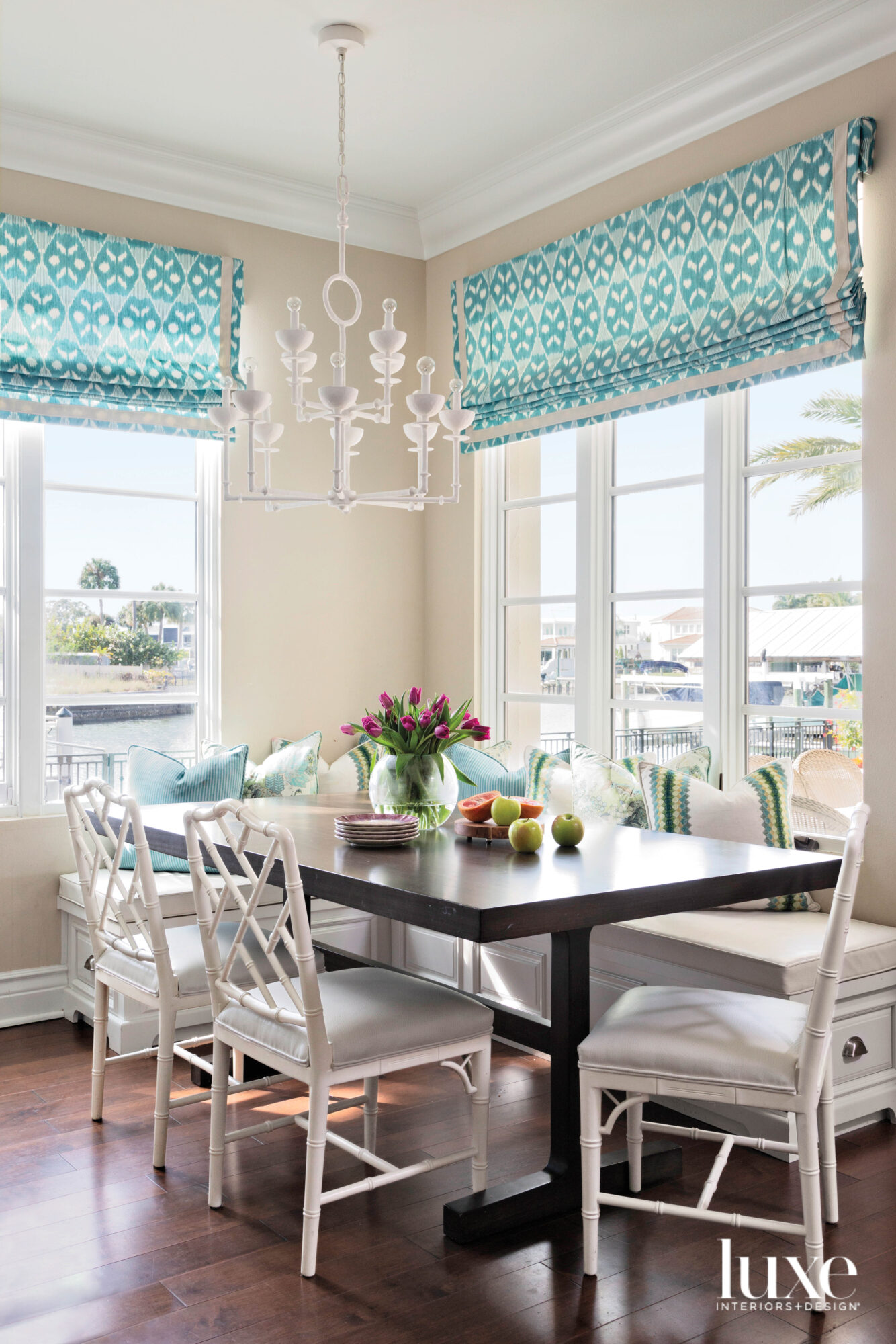 Breakfast nook with banquette, wood table and blue patterned window shades.