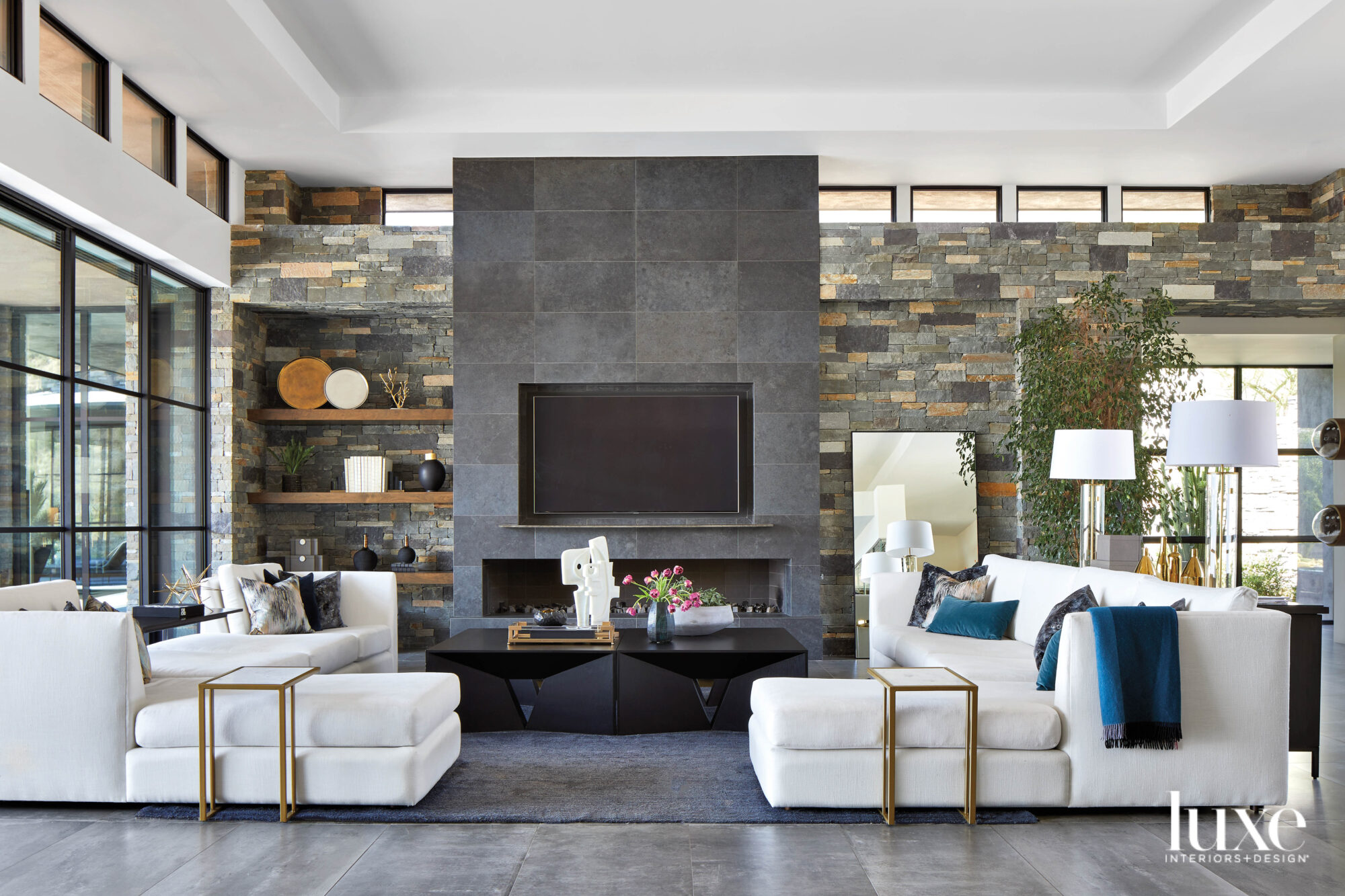 A living area with white couches and a dark stone fireplace.