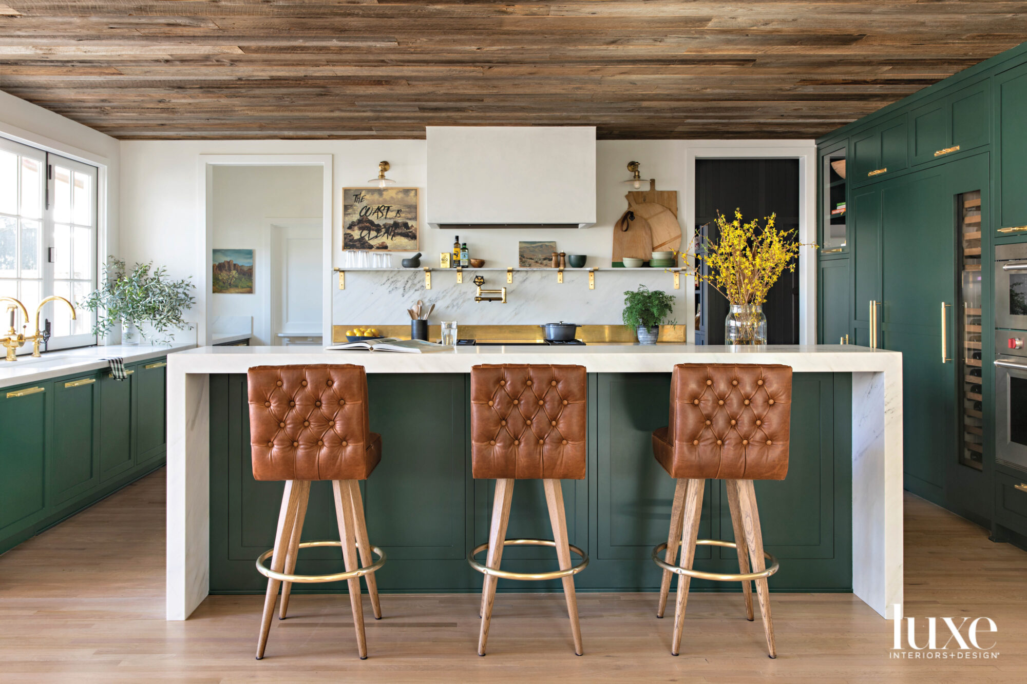 hunter green kitchen with camel leather barstools and brass accents