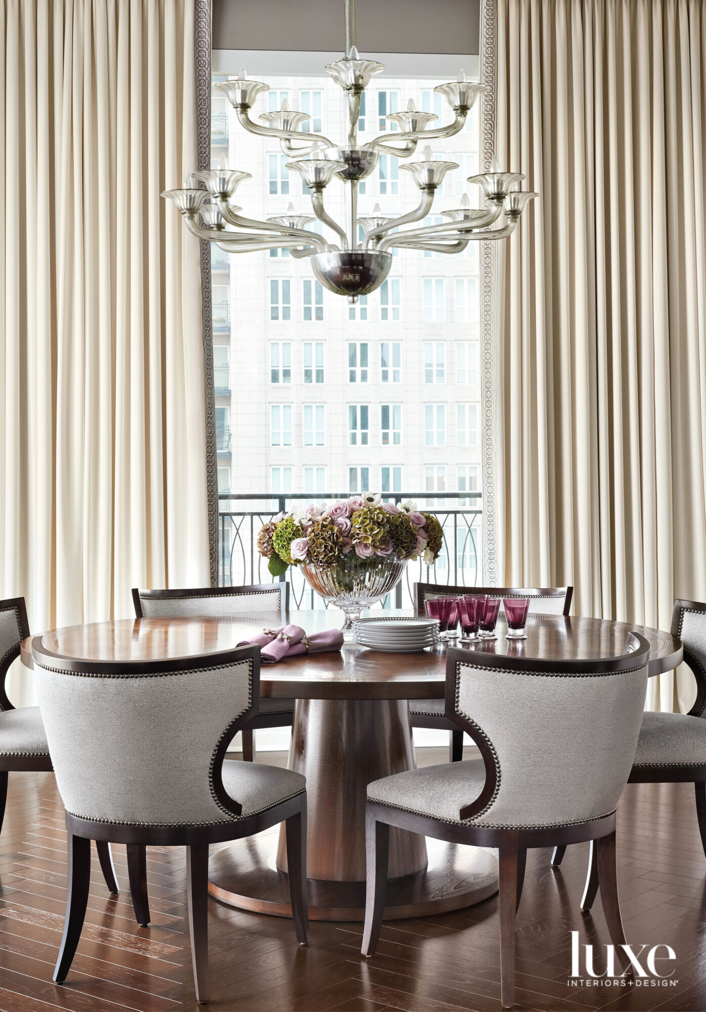 A dining room with a round dark wood table and upholstered chairs.