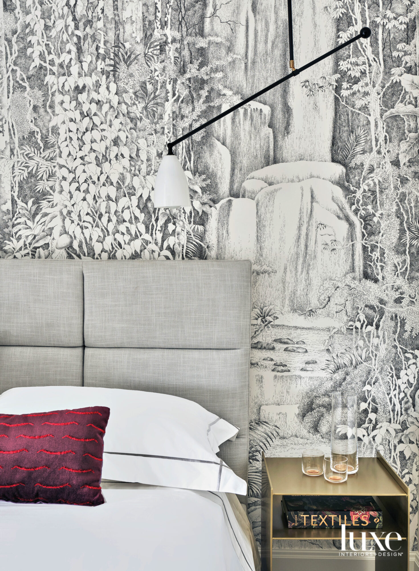 A gray bed with a black-and-white mural behind it.