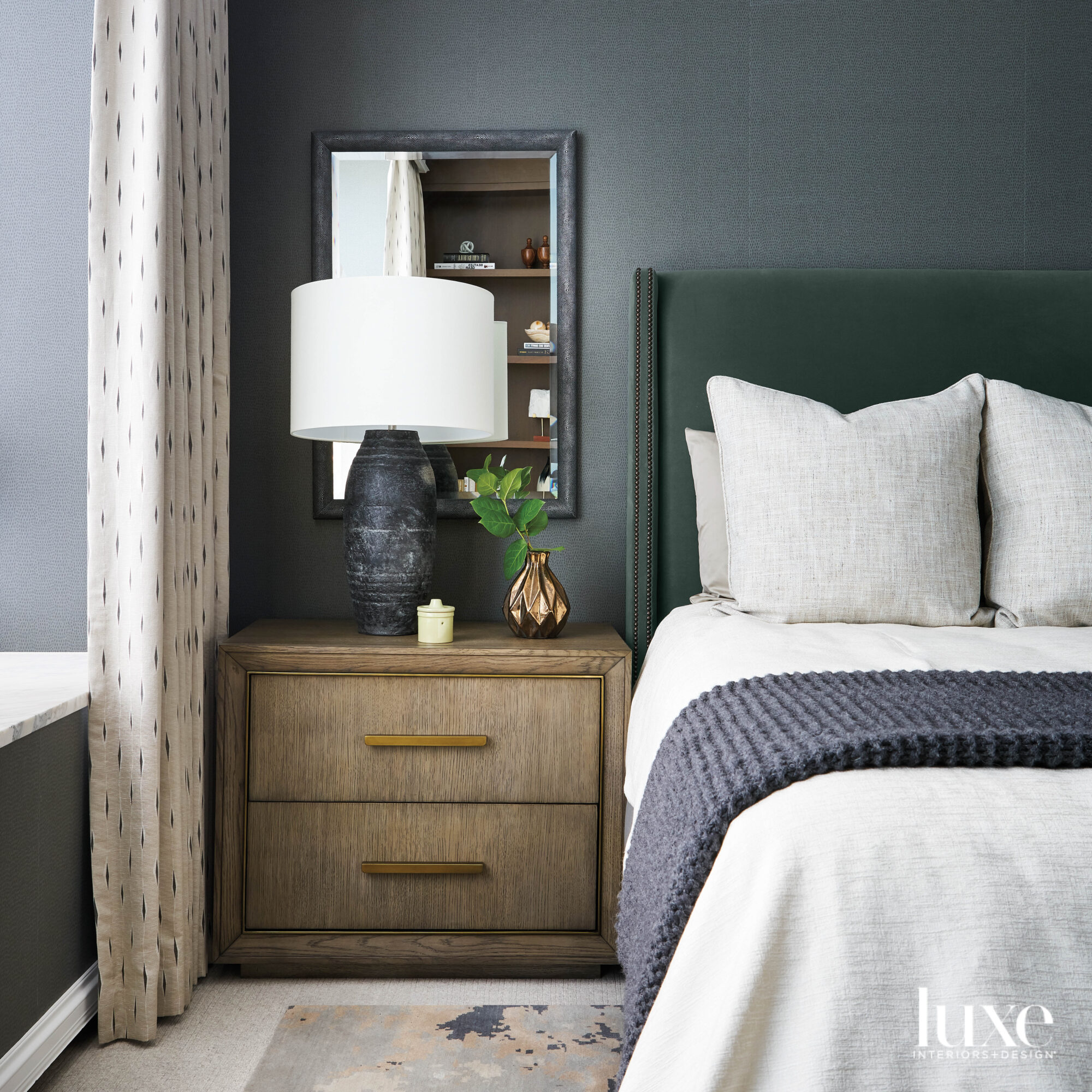 A bedroom with gray walls and a green upholstered bed.