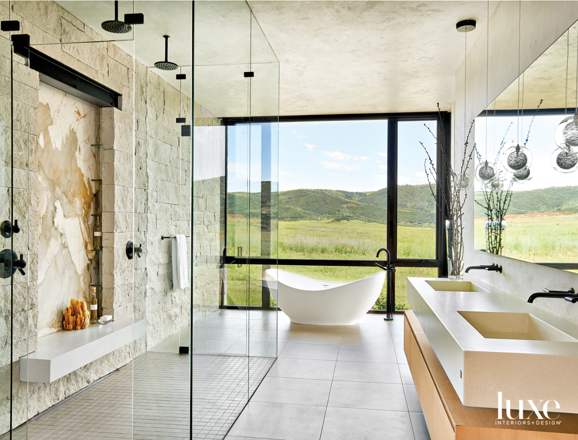 A white tub sits between stone walls in the spacious main bath.