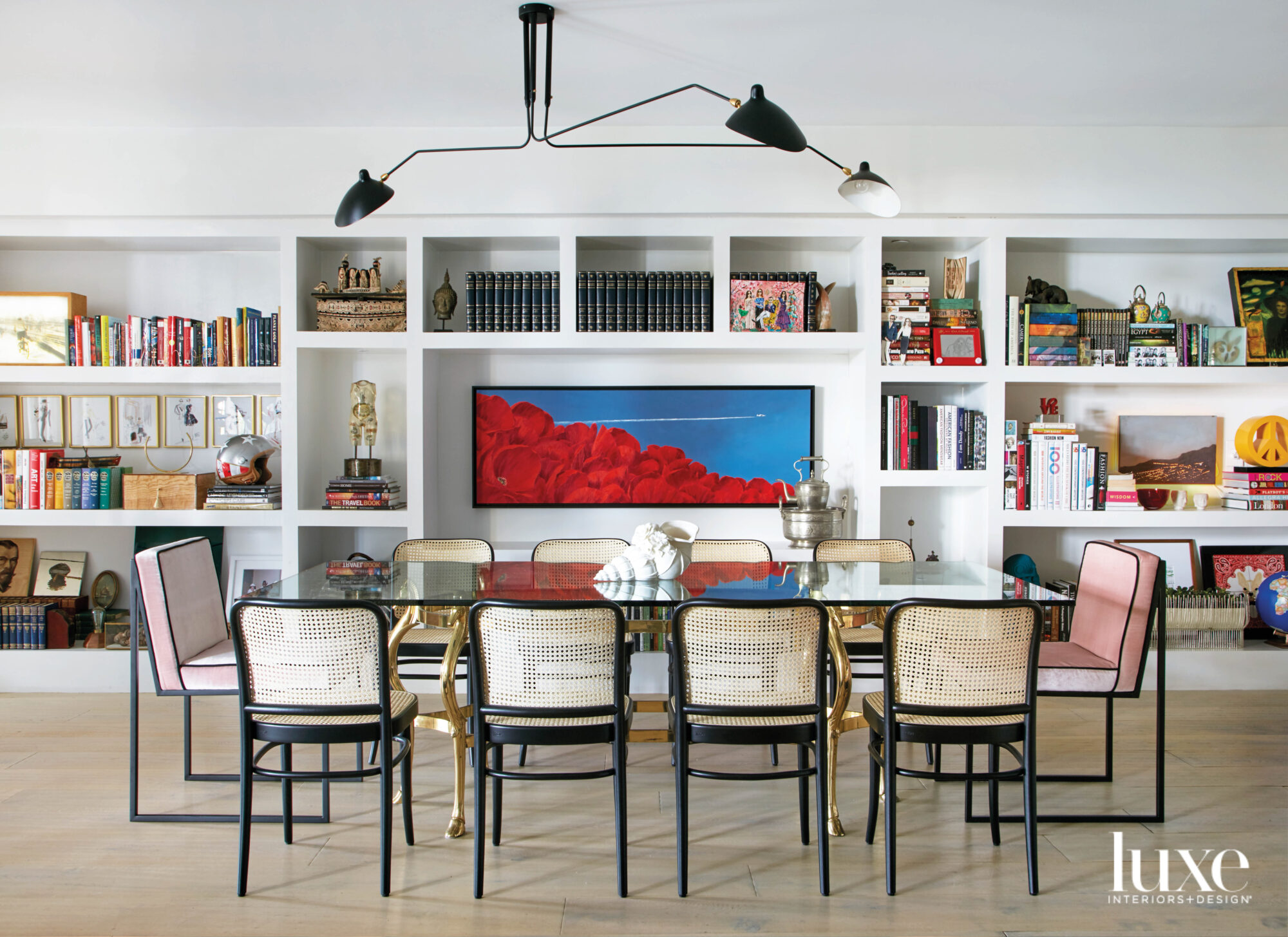 dining area with black wire chandelier, white built-in shelving and blue and red artwork
