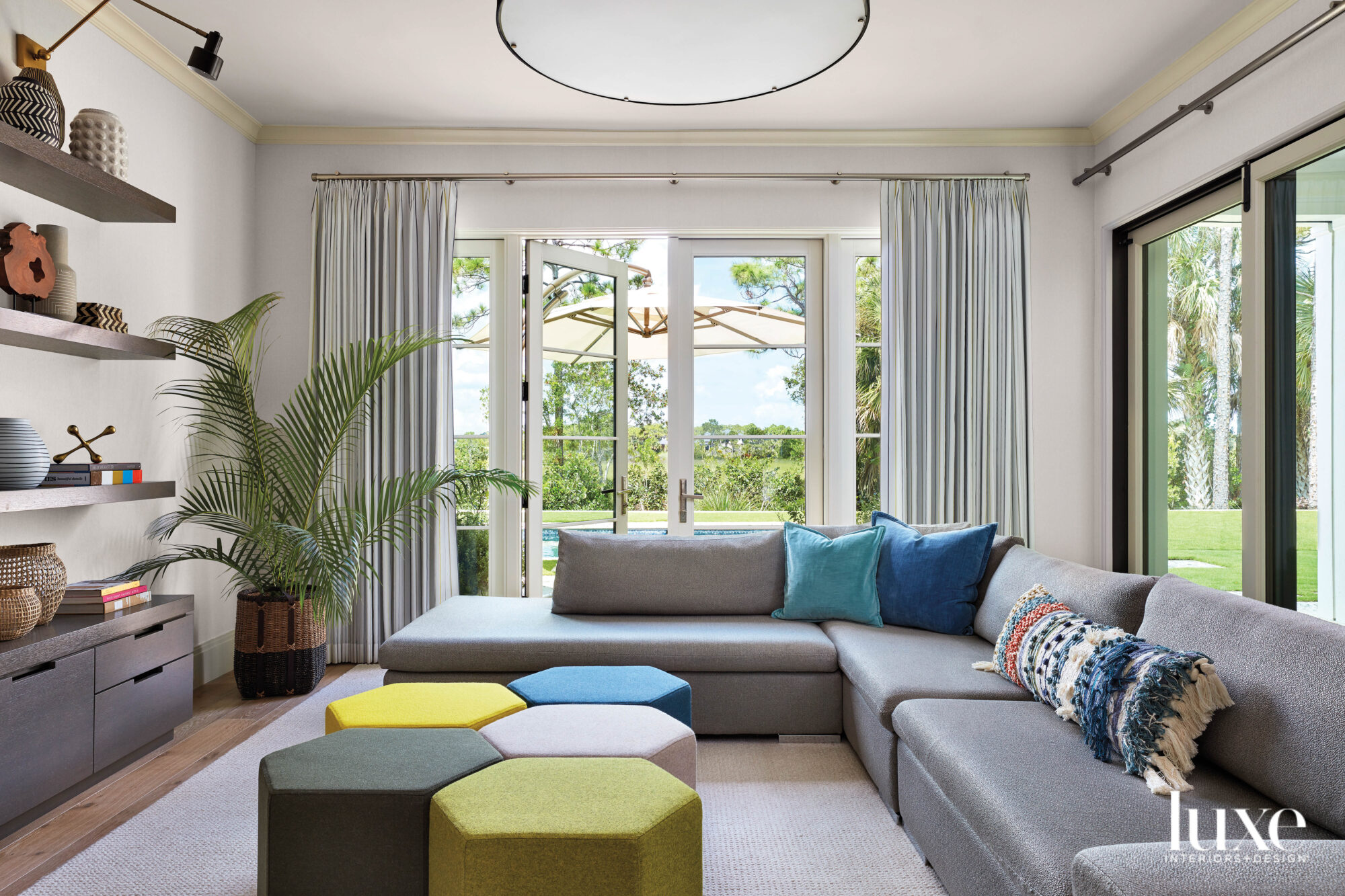 family room with large gray sectional and octagonal ottomans in blue and green