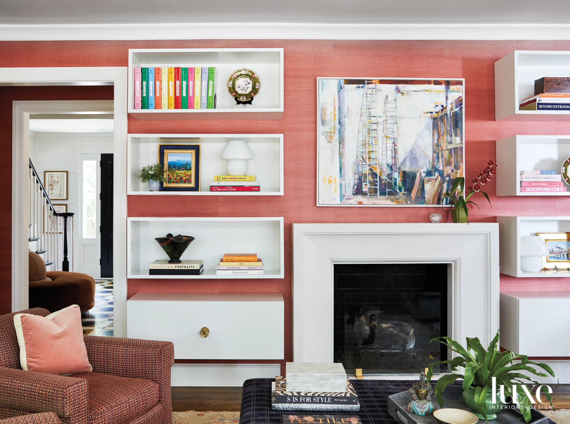 wall with salmon-colored grasscloth wall covering, floating bookshelves and fireplace