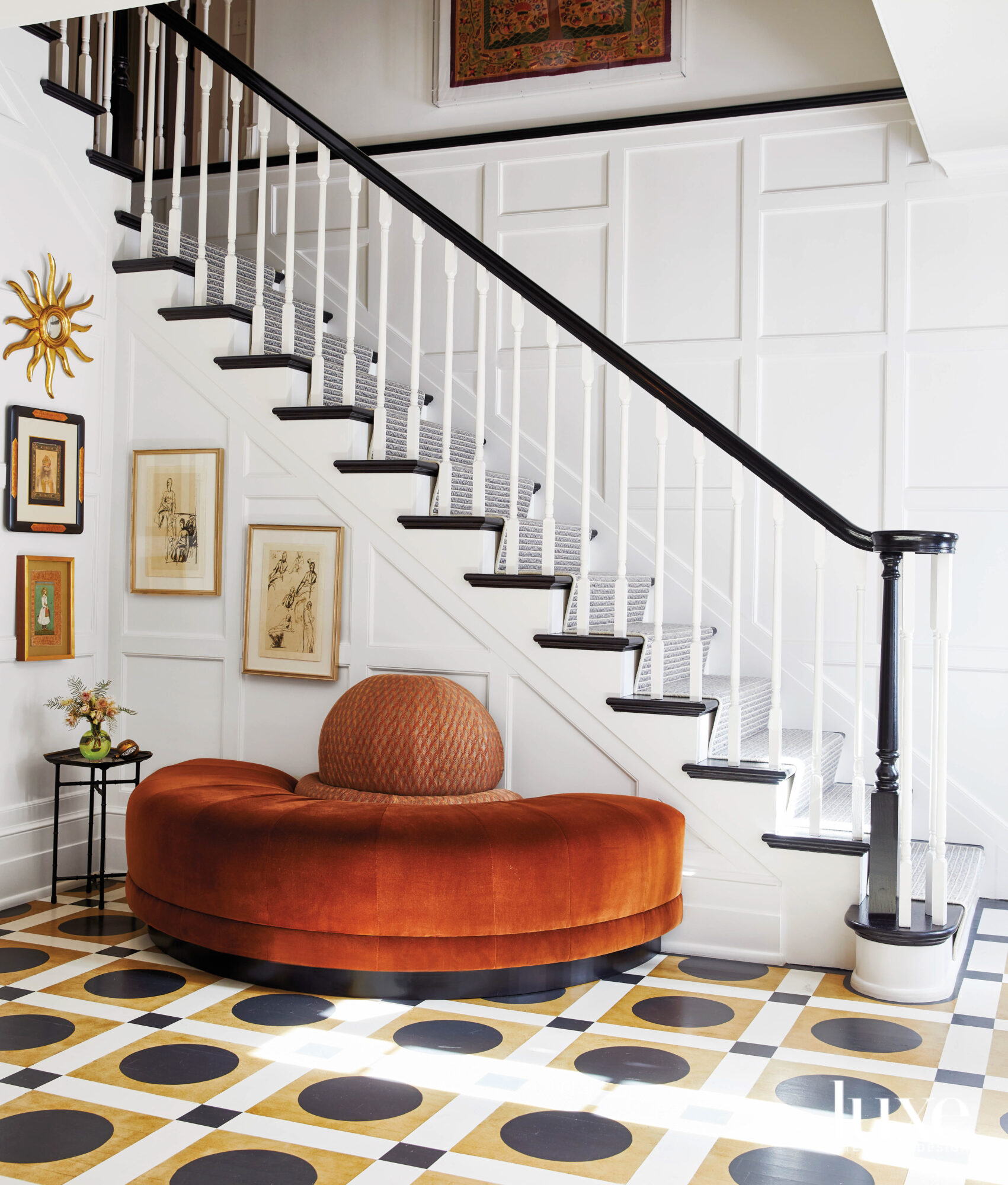Dramatic stairwell with painted black-and-white floors, rust-colored semicircular bench and paneled walls