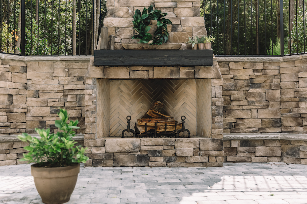 Custom hardscape design with pavers and oversized conventional fireplace on an outdoor patio by FireRock