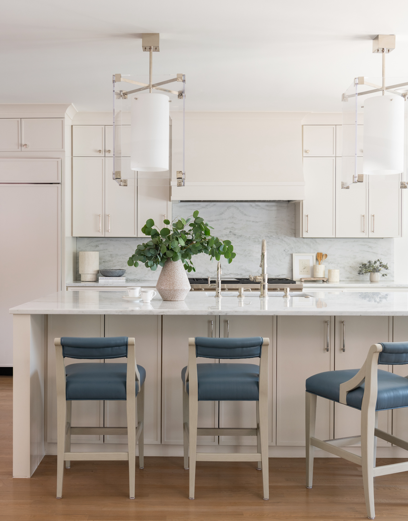 A kitchen with white cabinets and blue chairs.