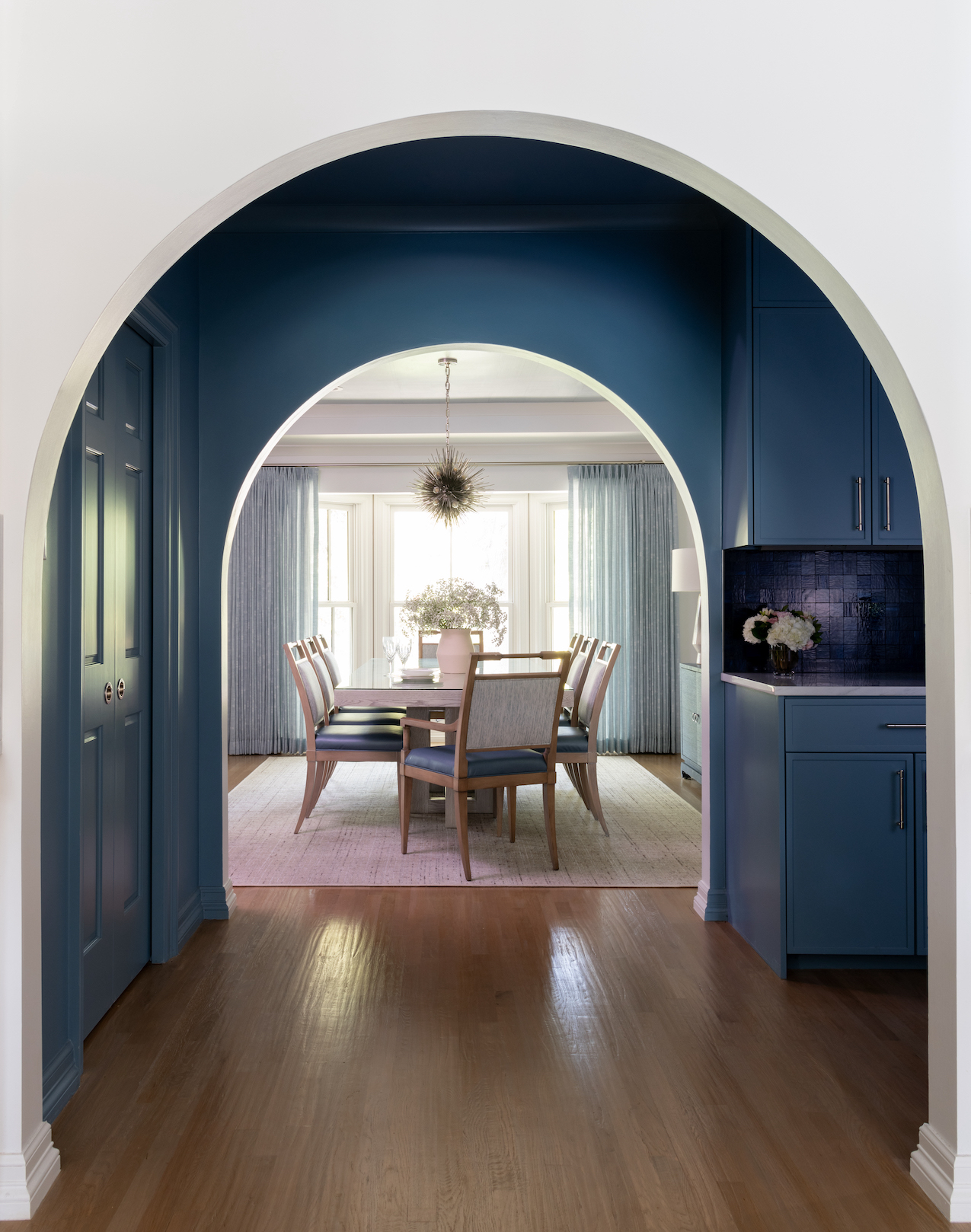 A dining room with blue walls and a table and chairs.