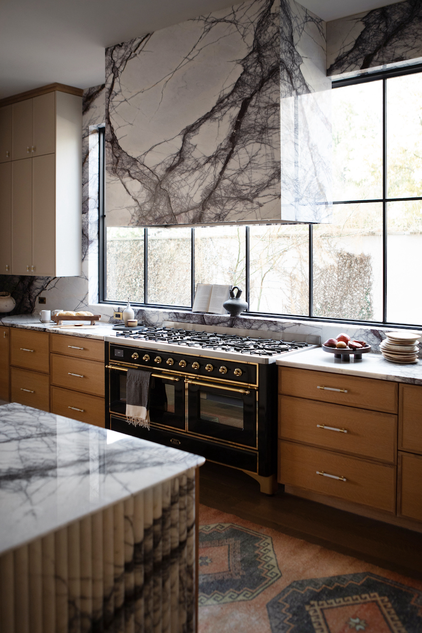 Sleek kitchen design with marble counter tops and a panoramic window for a bright atmosphere.