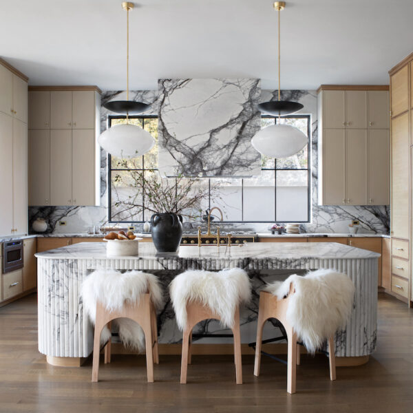 Kitchen with marble counter tops and white sheepskin chairs for island.