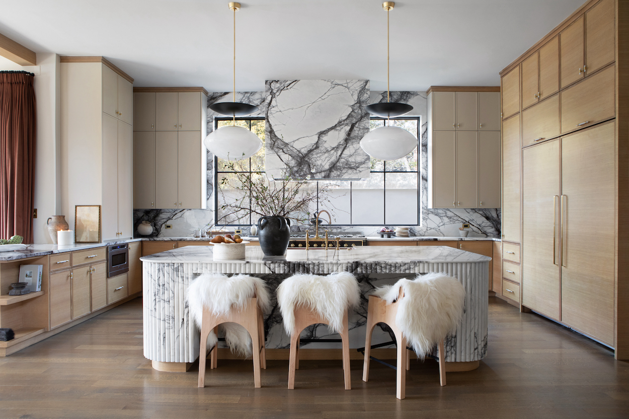 Kitchen with marble counter tops and white sheepskin chairs for island.