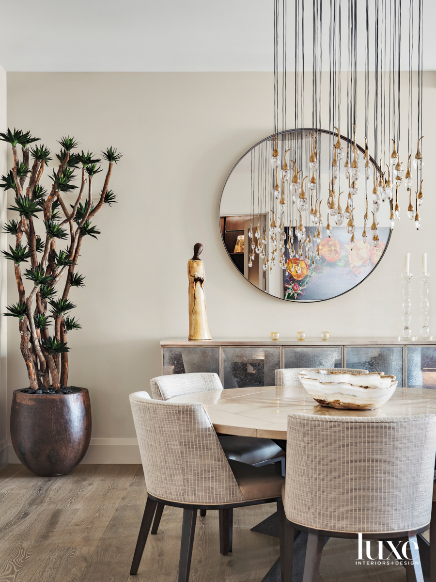 A dining room table with a glass bead chandelier above it.