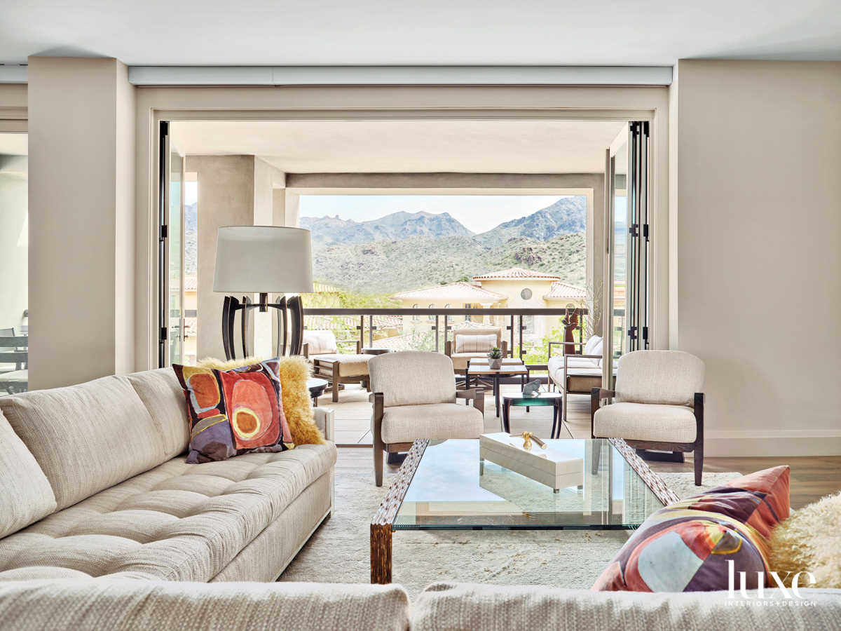 A living room with white seating and a view of mountains.