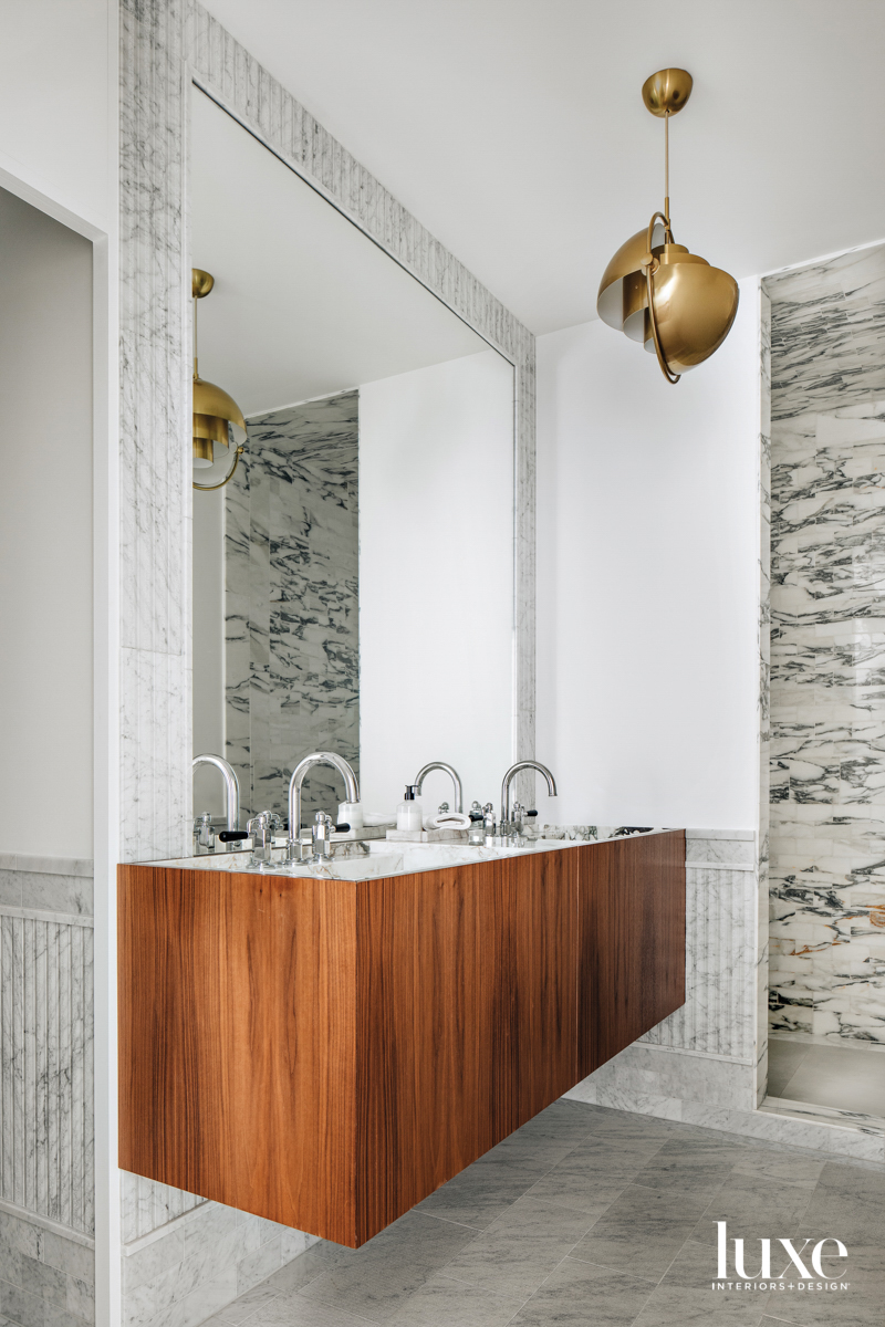 A wood vanity in a marble bathroom.