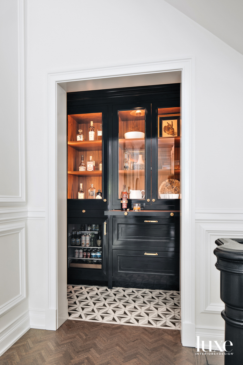 A black laquered bar area with a patterned floor tile.