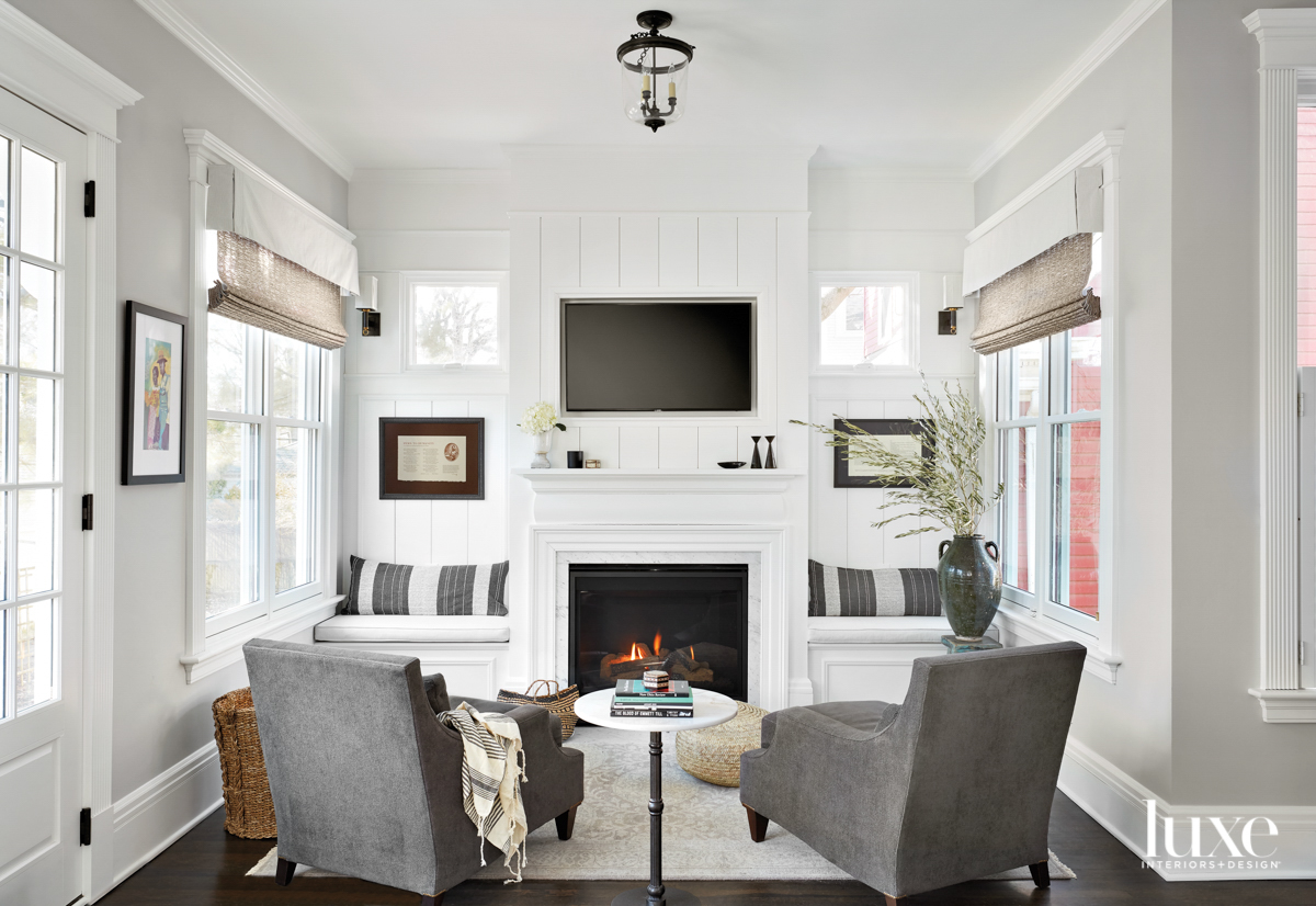 Two gray chairs face a white fireplace.