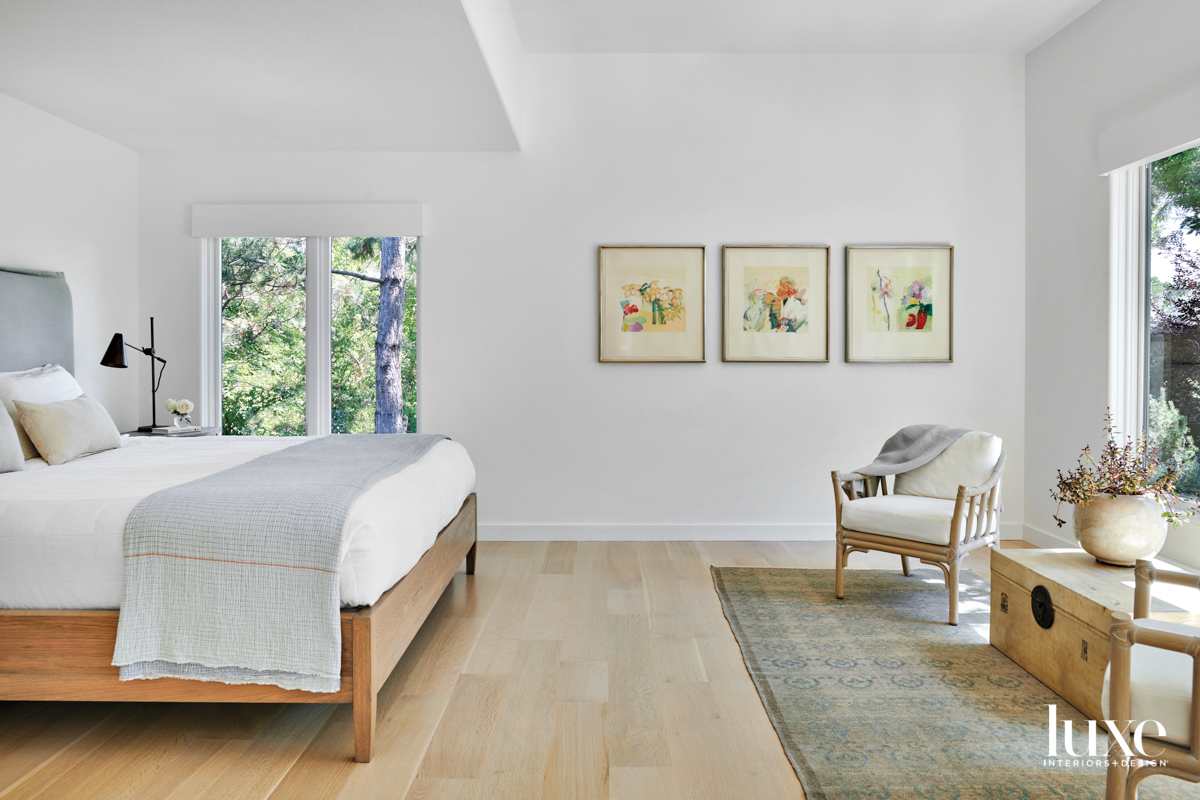 primary bedroom with white walls, paintings and bed designed by Mosaic Architects + Interiors