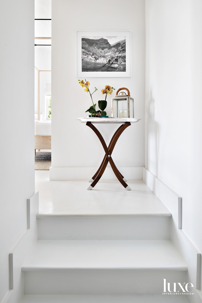 steps to primary bedroom with side table beneath black and white photograph