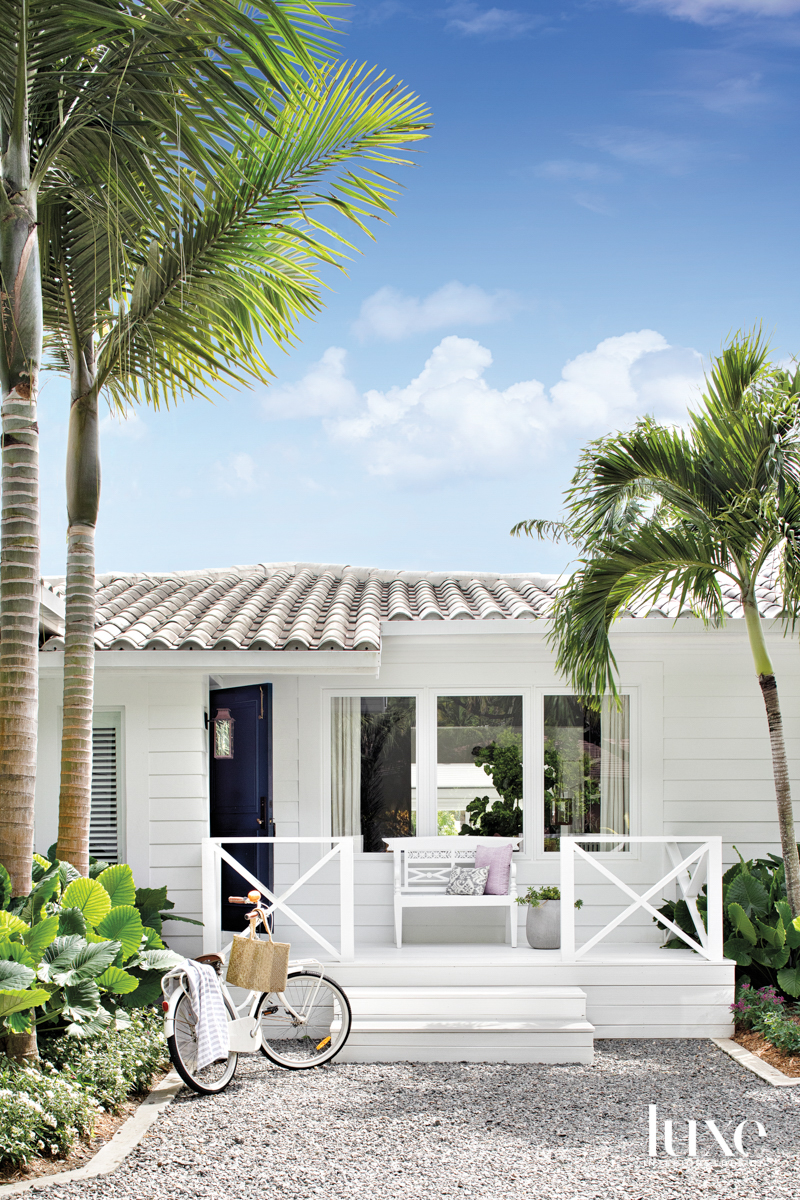 front exterior of white bungalow with palm trees