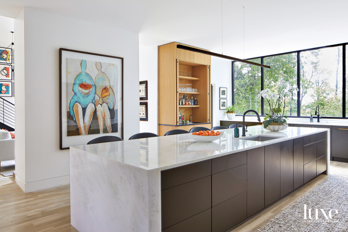 Modern kitchen with waterfall marble countertops, built-in bar and abstract figurative artwork on wall