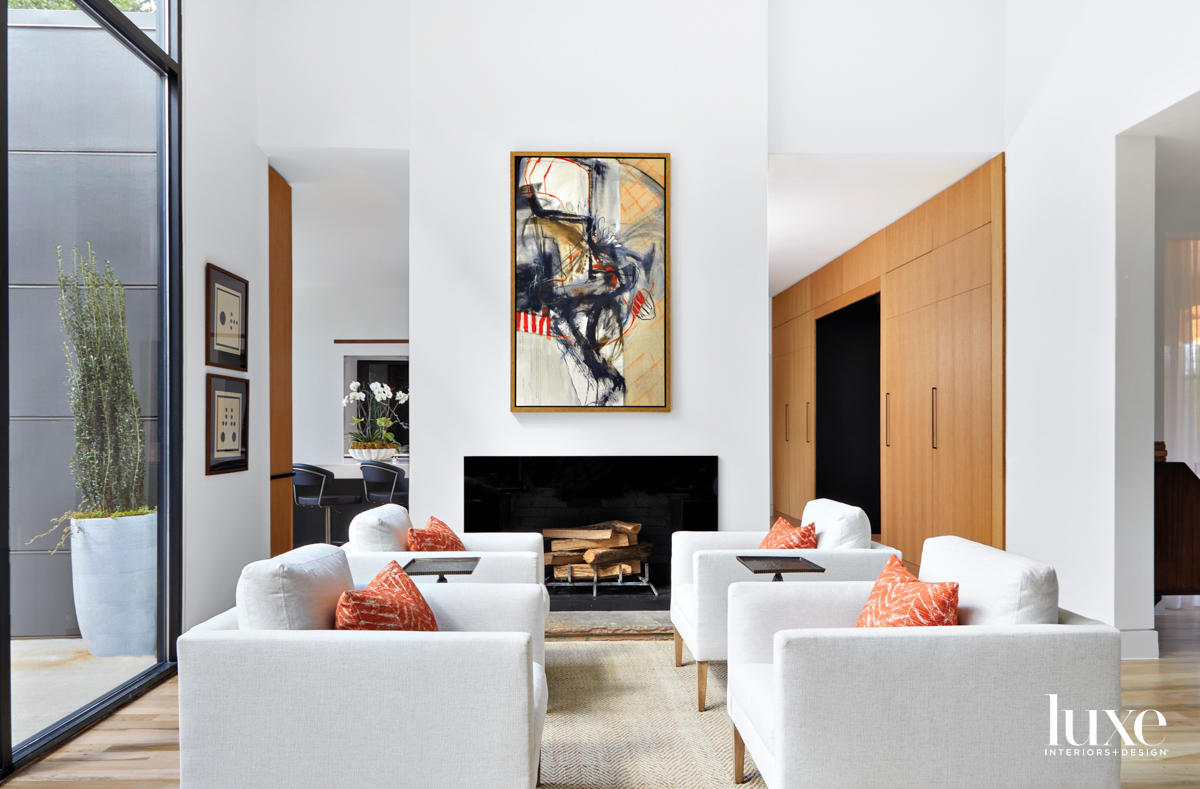 Living room with four club chairs, orange pillows, abstract artwork and white oak cabinetry