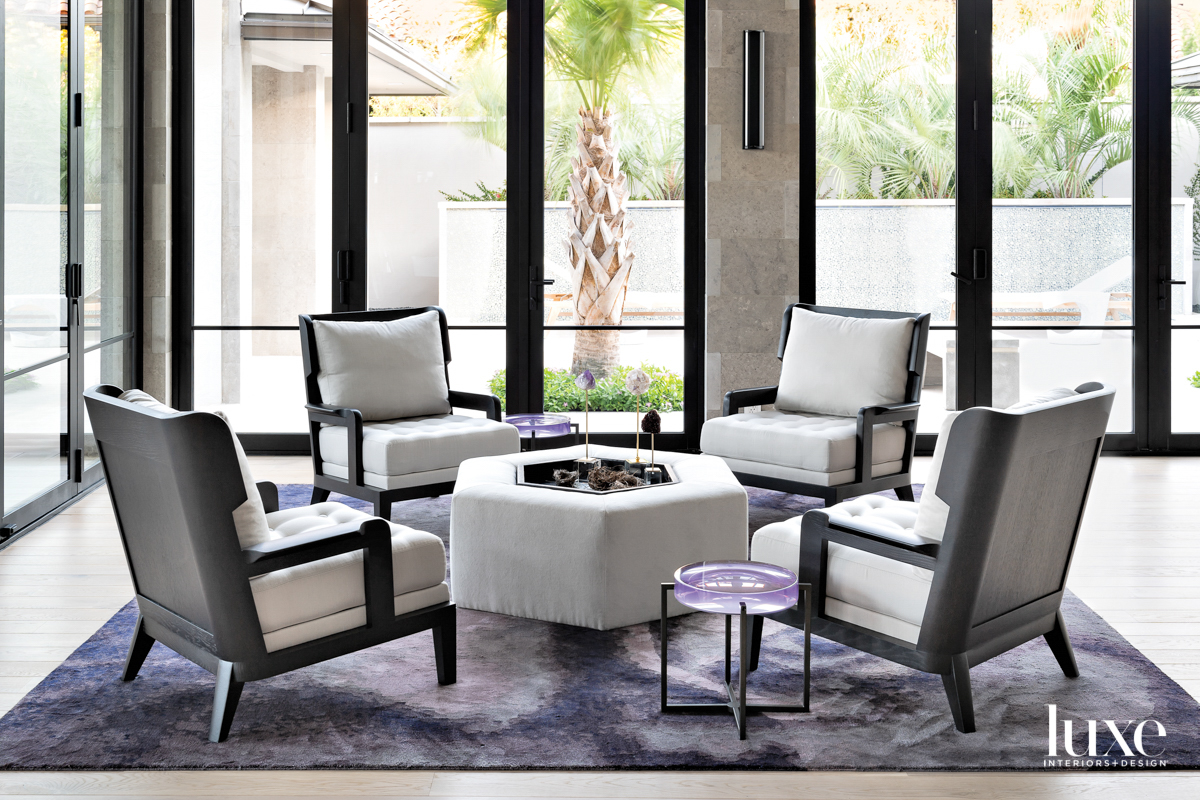Seating area with chairs, an ottoman and a purple rug.
