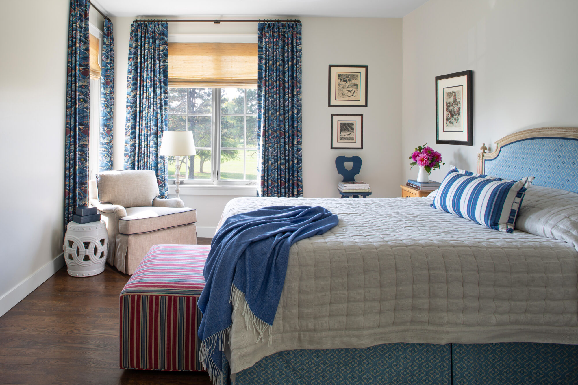 A guest bedroom has a pale blue, berry red and white color palette.