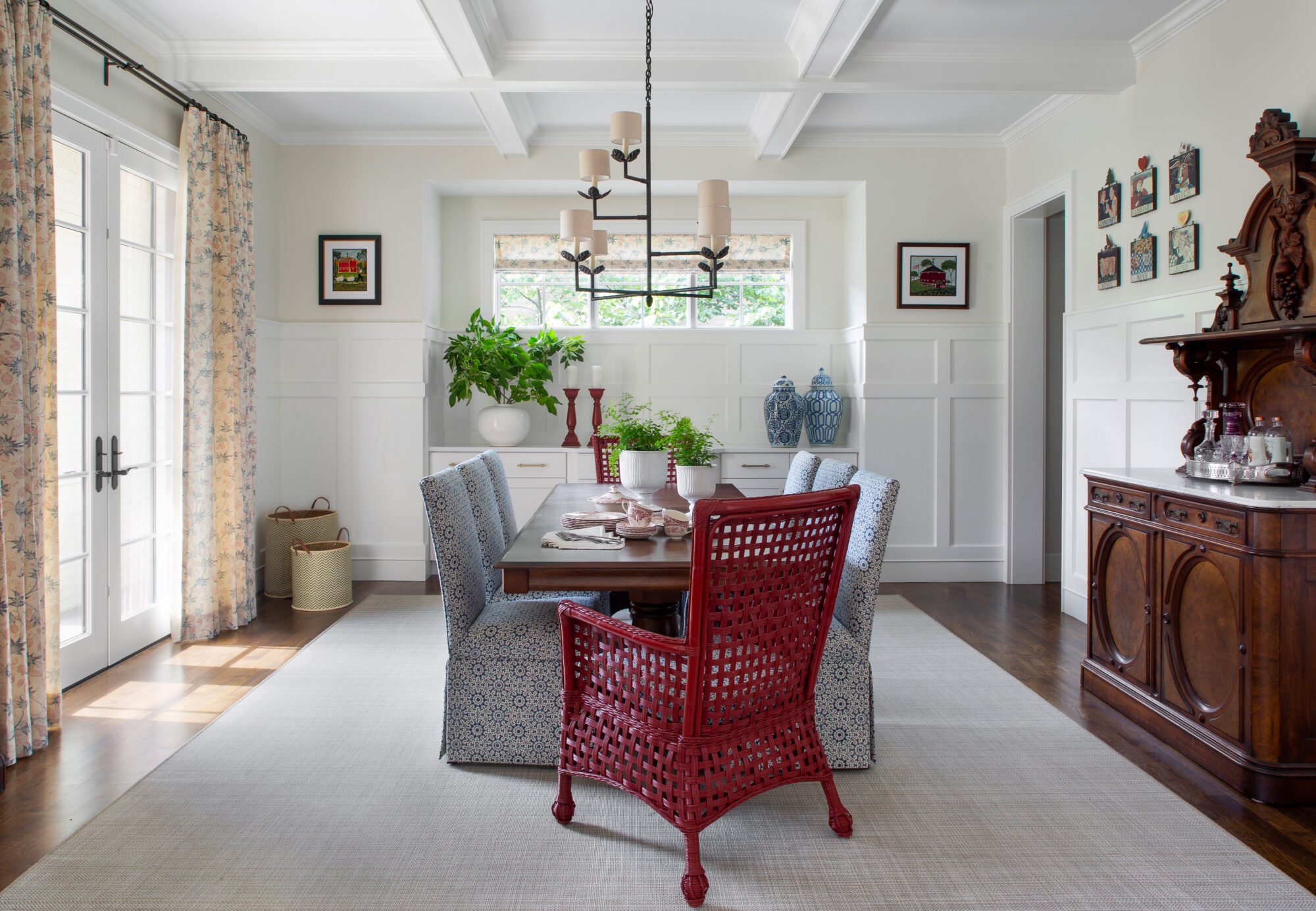 A dining room has a long table with blue dining chairs and red wicker captain chairs.