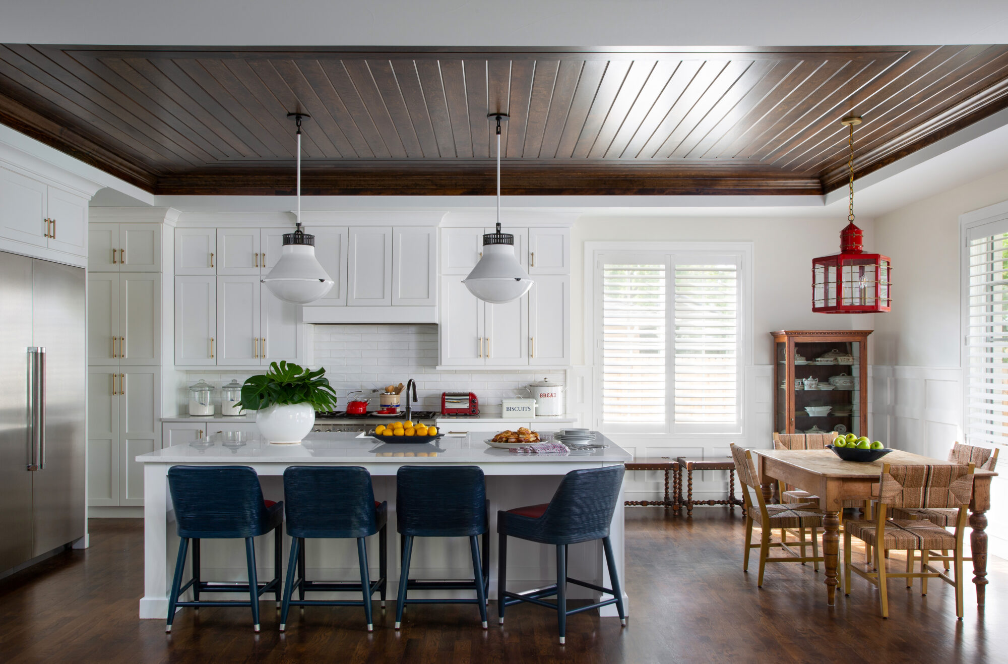 A large kitchen has a dark-wood ceiling and white cabinets.