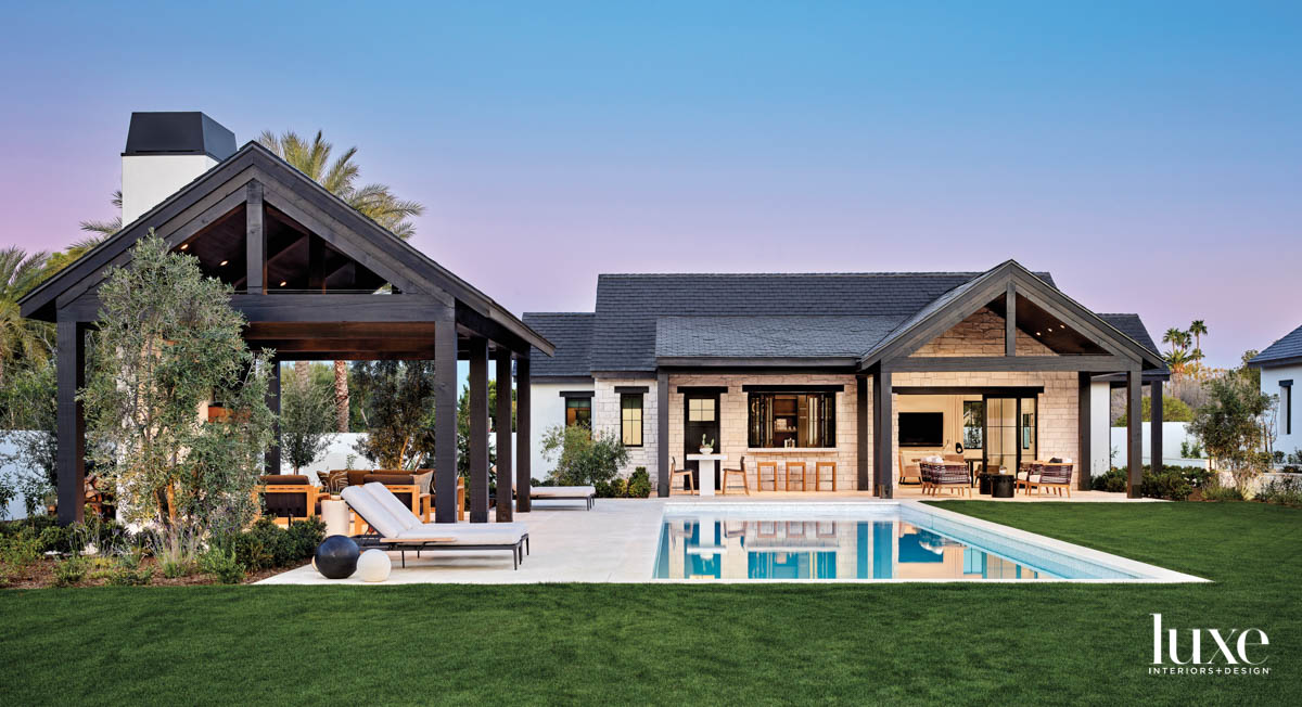 black modern farmhouse exterior with outdoor entertaining spaces a pool at twilight
