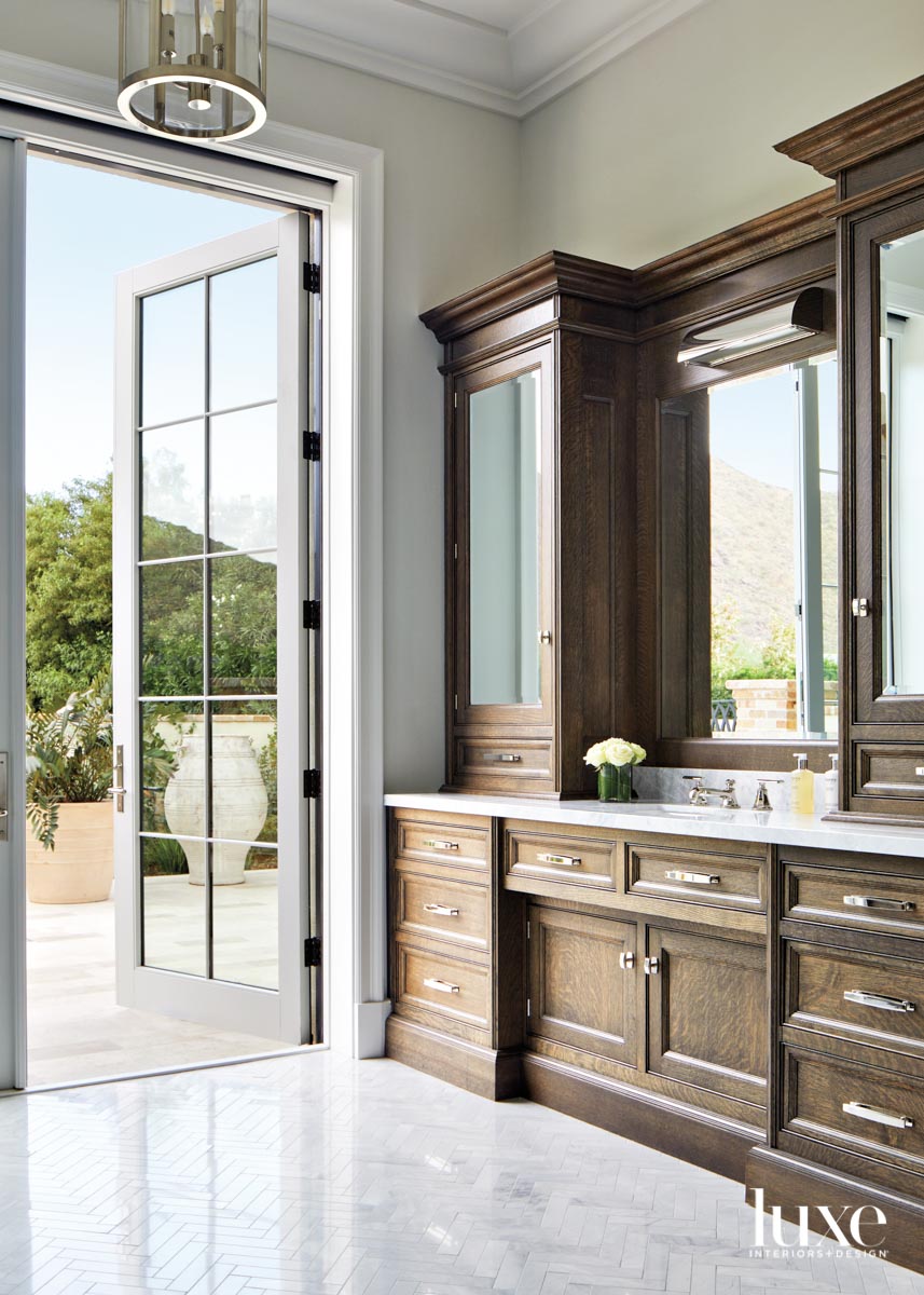A bathroom with dark wood vanity. The door opens to the outside.