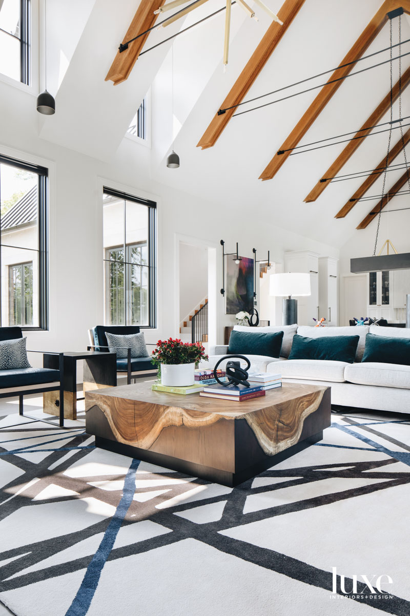 living room with a graphic rug, white couch, armchairs and a wood coffee table for an organic touch